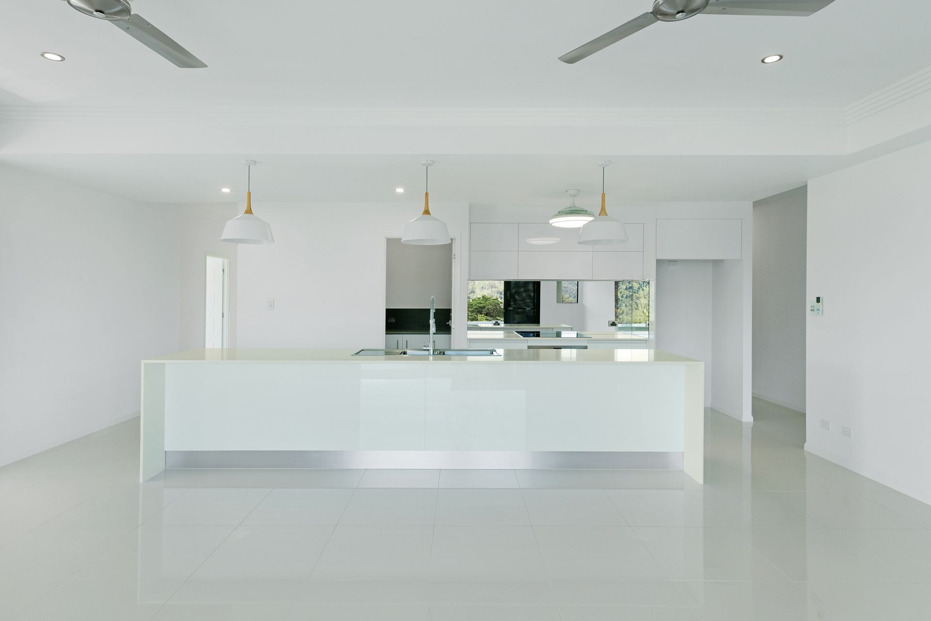 Minimalist, All-white Kitchen With a Large Island, Pendant Lights — Ashlee Jones Homes in Gordonvale, QLD