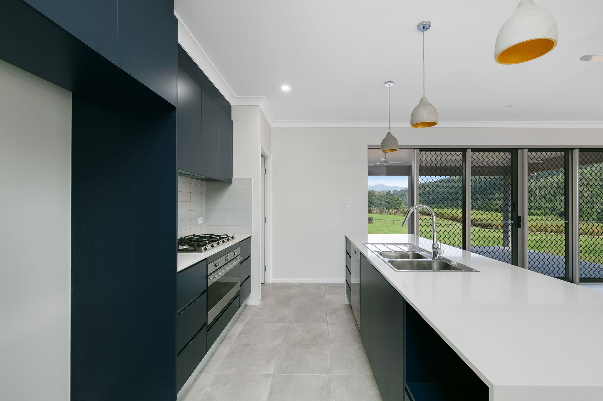 A Modern Kitchen Featuring Matte Dark Blue Cabinets — Ashlee Jones Homes in Gordonvale, QLD