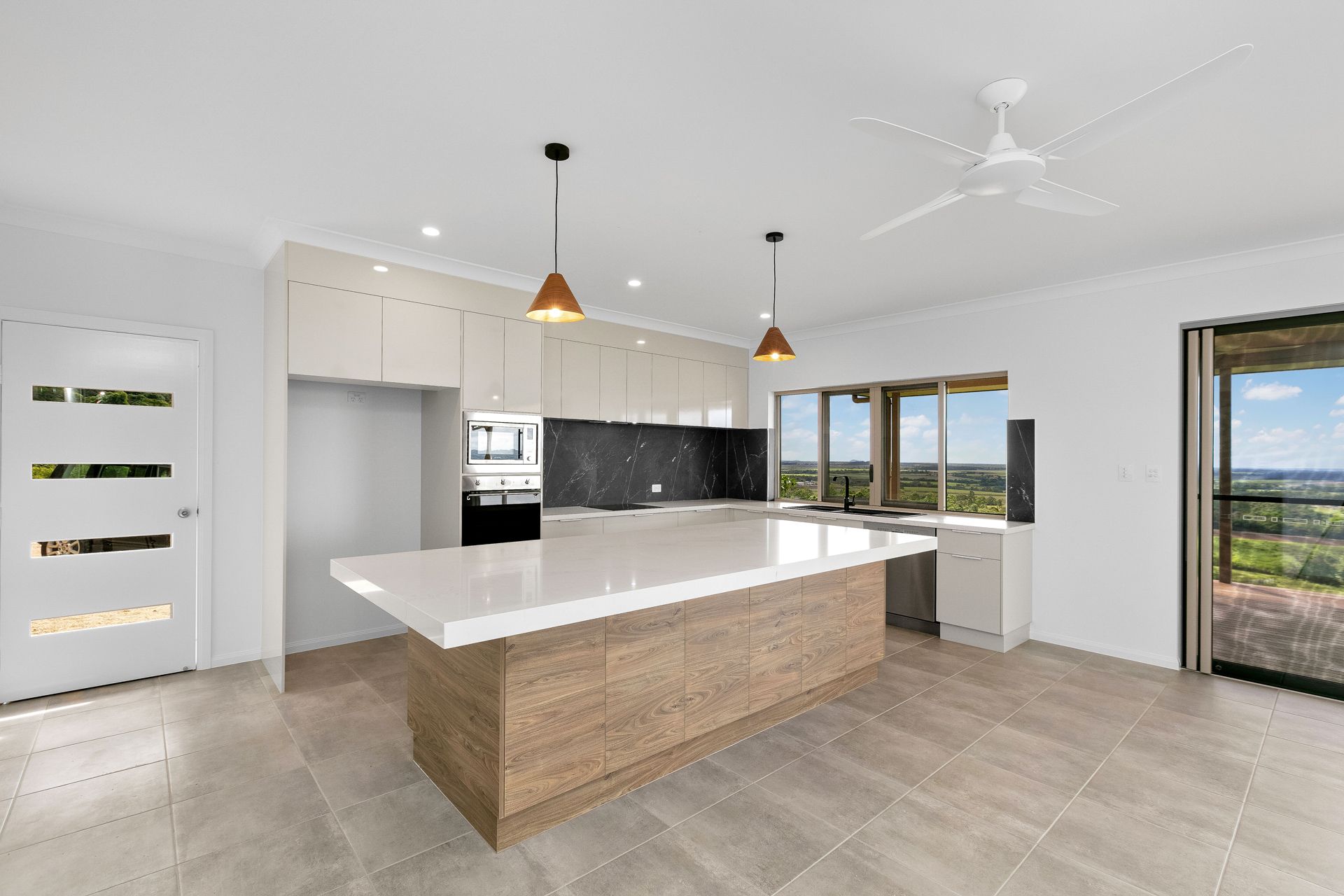 A Modern Kitchen With a Light Wood Island, White Countertops — Ashlee Jones Homes in Gordonvale, QLD