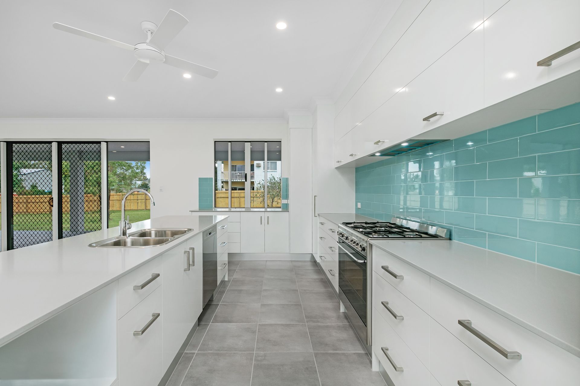 A Modern White Kitchen Featuring an Island, Grey Tile Floors — Ashlee Jones Homes in Gordonvale, QLD