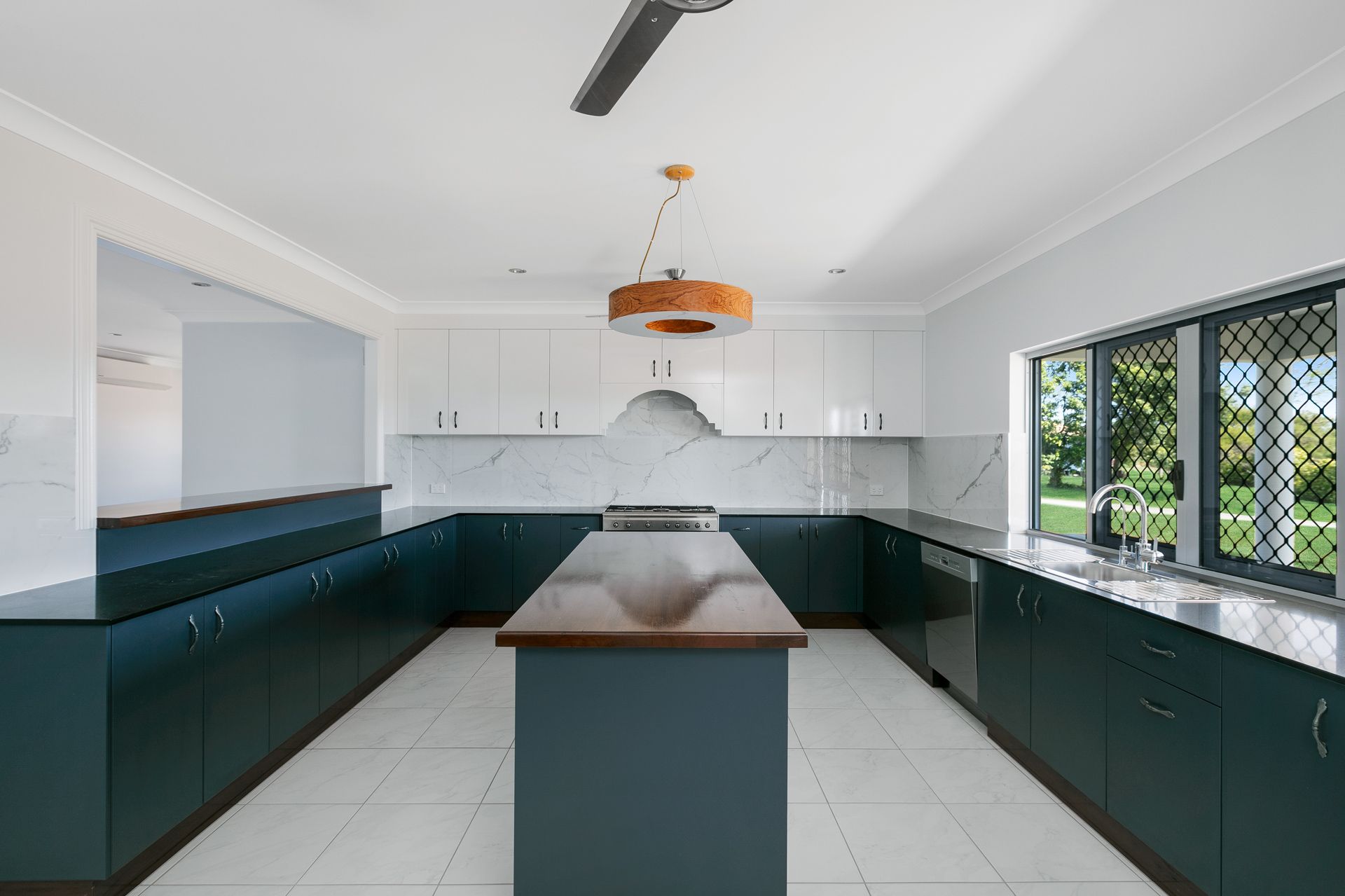 Modern Kitchen With Dark Teal Base Cabinets — Ashlee Jones Homes in Gordonvale, QLD
