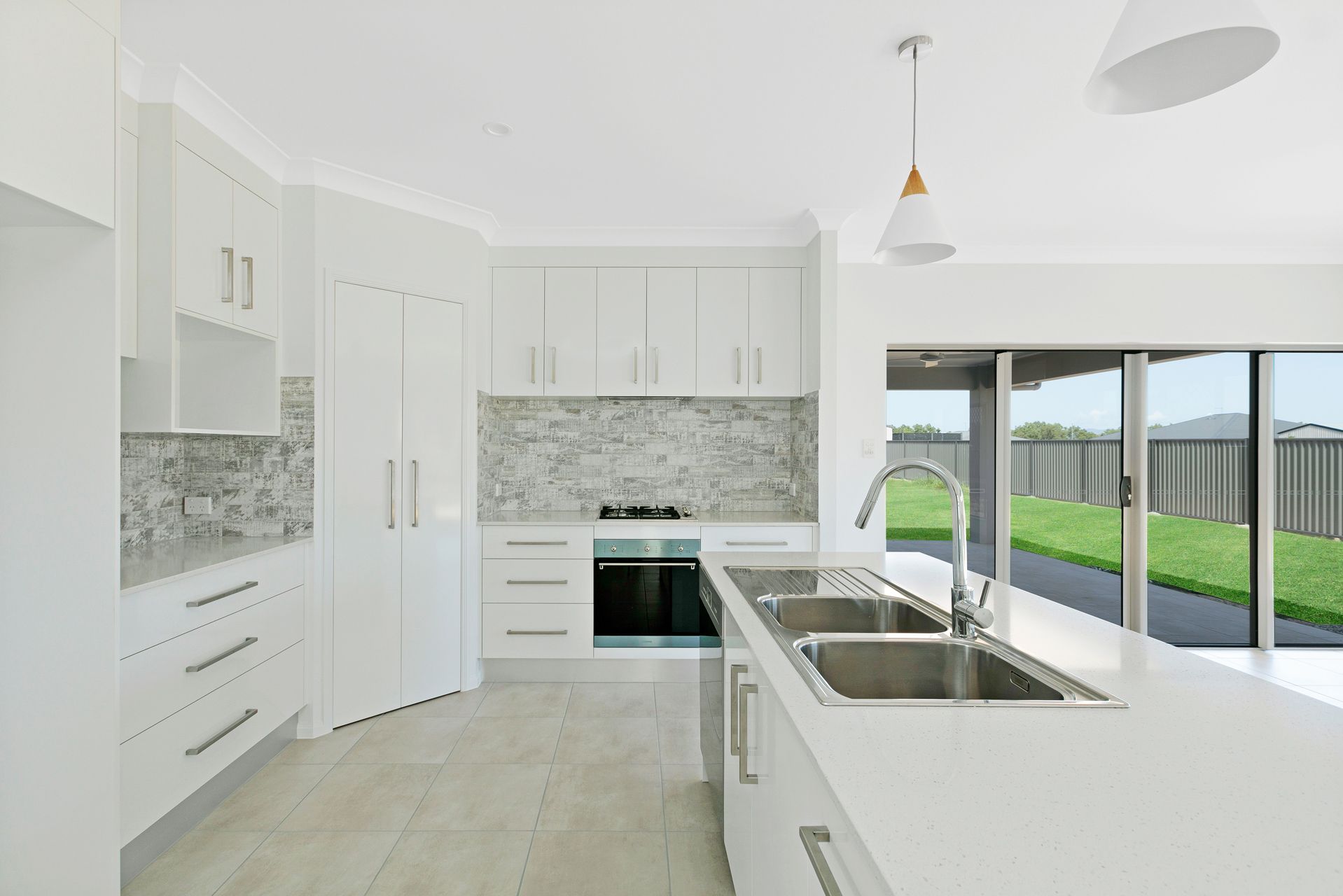 A Modern Kitchen With White Cabinets, Stone Countertops — Ashlee Jones Homes in Gordonvale, QLD