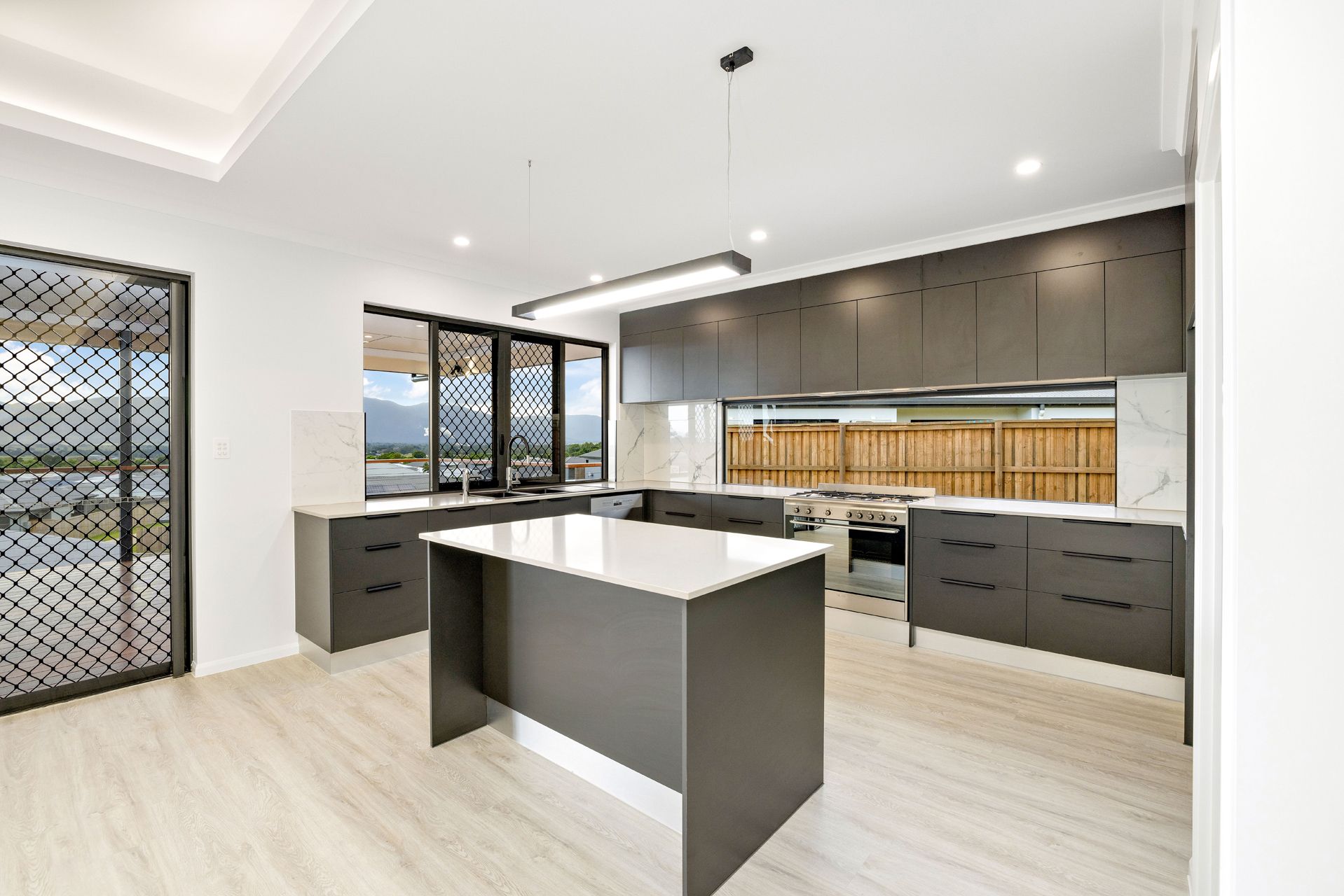 Modern Kitchen With a Central Island, Dark Charcoal Cabinetry — Ashlee Jones Homes in Gordonvale, QLD