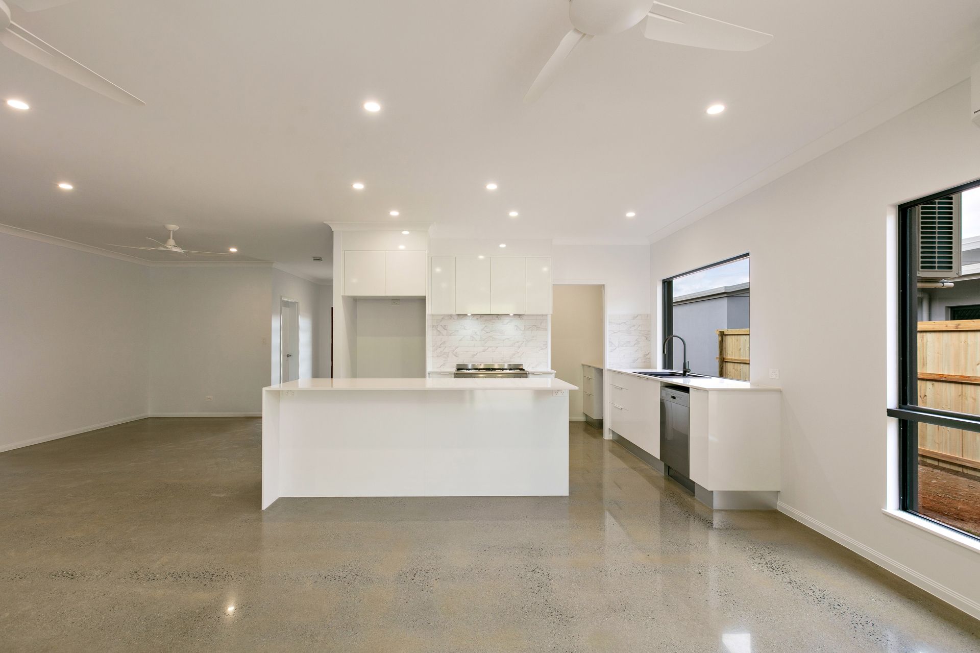 A Modern, Open-plan Kitchen and Living Area Featuring White Cabinetry — Ashlee Jones Homes in Gordonvale, QLD