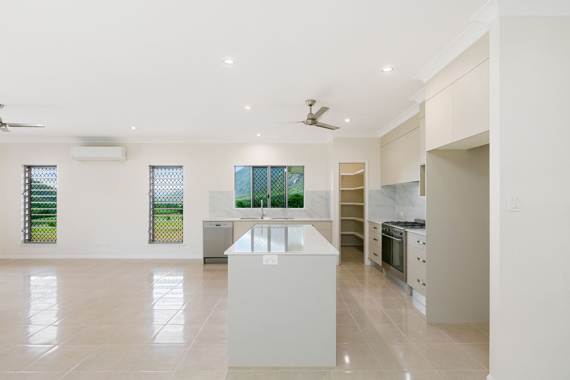 A Modern, Open-plan Kitchen and Living Area With Beige Tiled Floors — Ashlee Jones Homes in Gordonvale, QLD