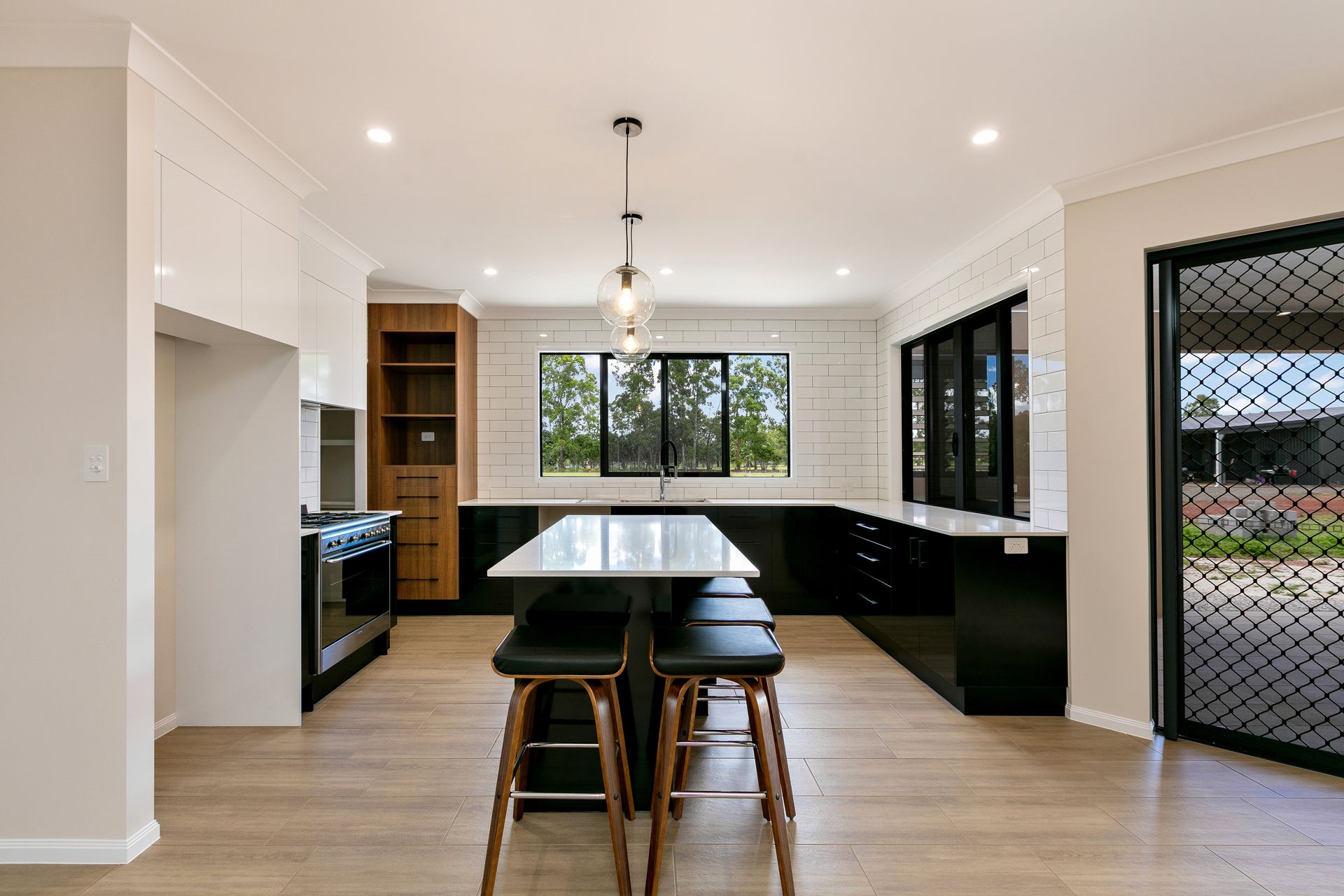 A Modern Kitchen With a Central Island, Black Cabinetry — Ashlee Jones Homes in Gordonvale, QLD