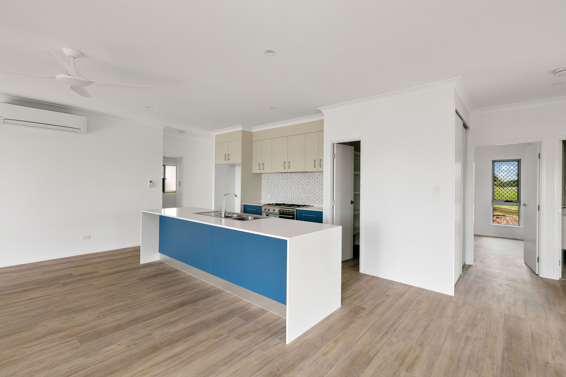 An Open-plan Interior Showing a Kitchen With a Blue Island Counter — Ashlee Jones Homes in Gordonvale, QLD