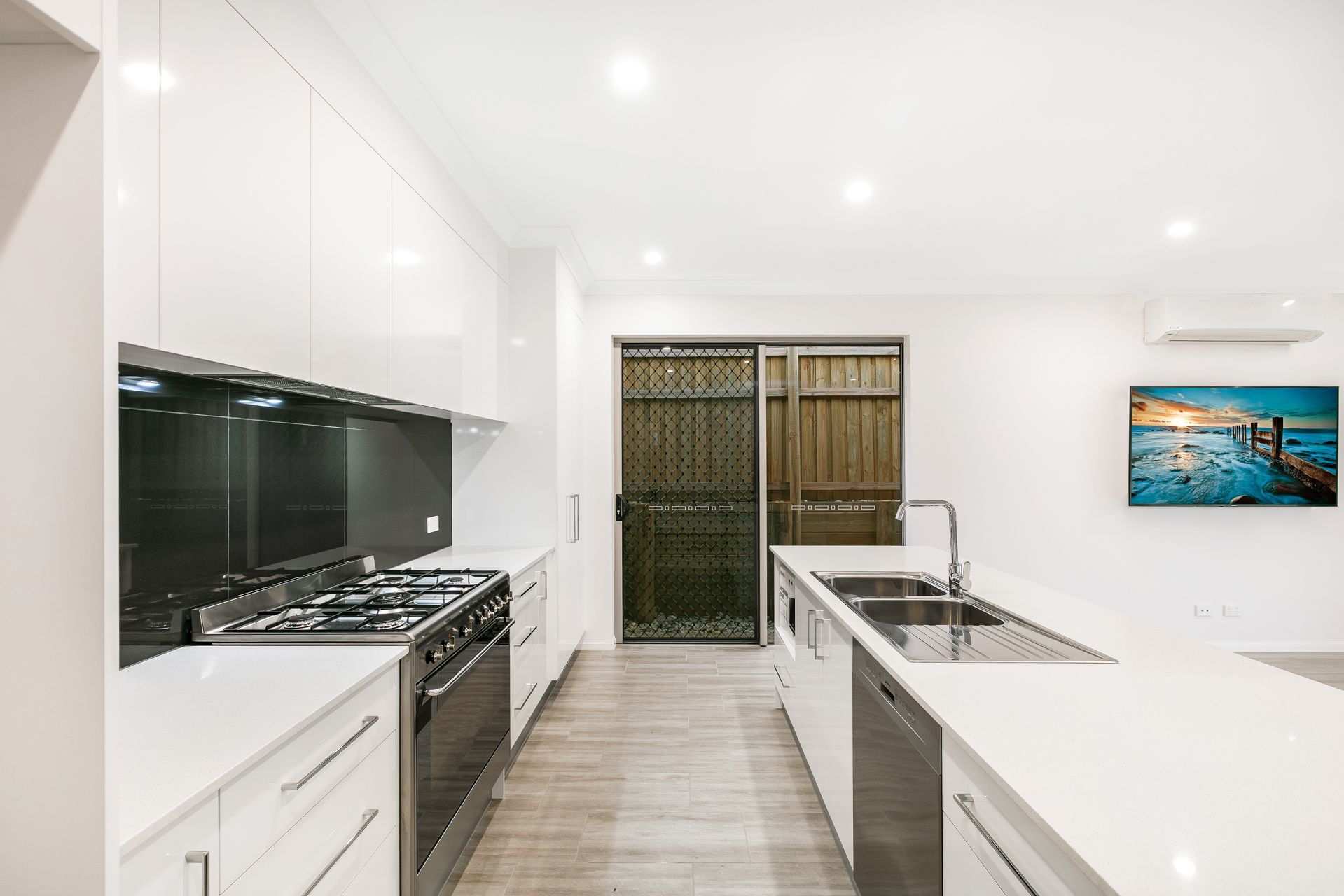 A Modern Kitchen Featuring White Cabinets, a Black Backsplash — Ashlee Jones Homes in Gordonvale, QLD