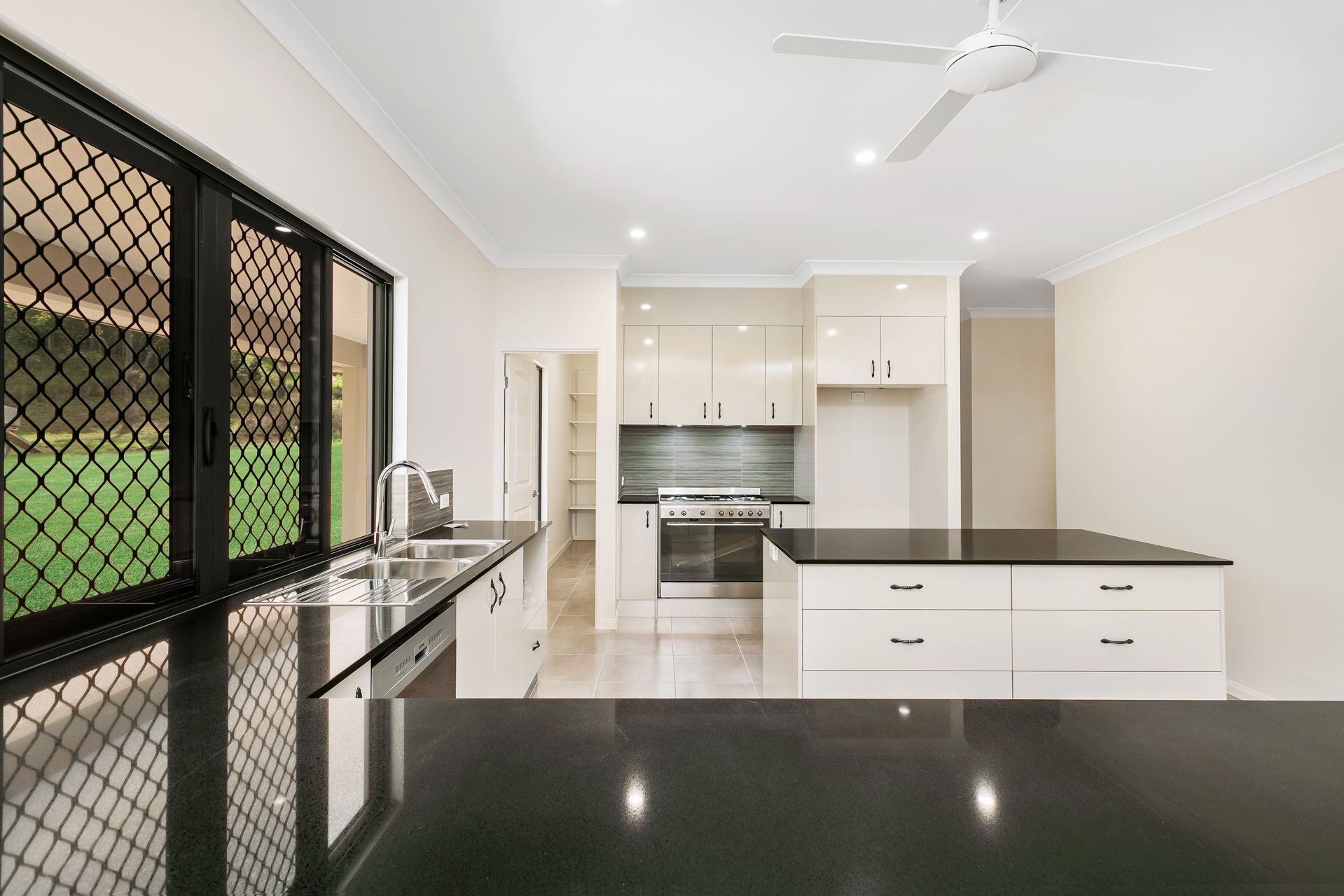 Modern Kitchen With Black Countertops, White Cabinets — Ashlee Jones Homes in Gordonvale, QLD