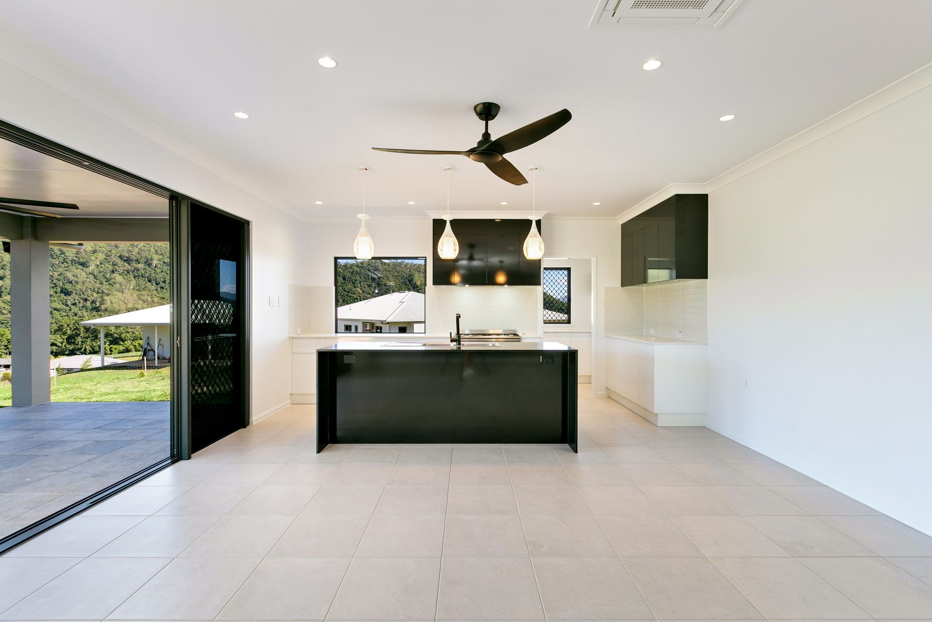 A Modern Kitchen With a Black Island, White Cabinets — Ashlee Jones Homes in Gordonvale, QLD