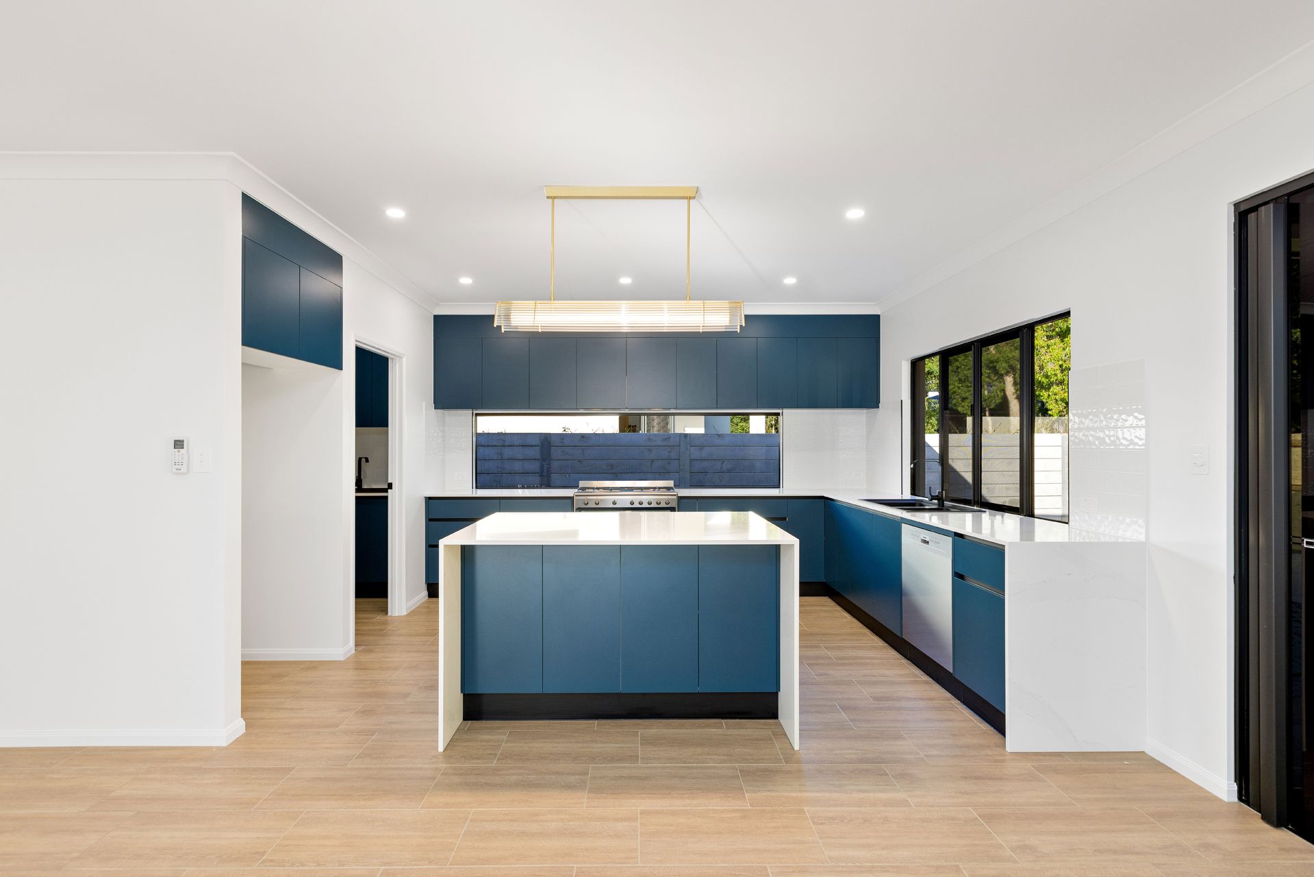 Modern Kitchen With Blue Cabinetry, a Large White Kitchen Island — Ashlee Jones Homes in Gordonvale, QLD