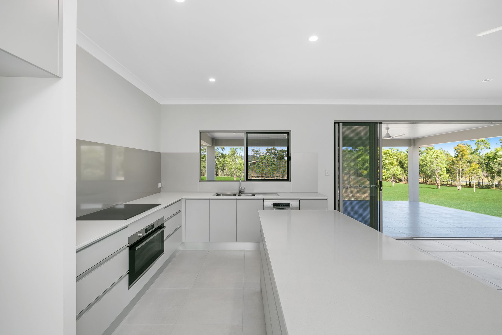 A Modern, Minimalist White Kitchen With a Large Island — Ashlee Jones Homes in Gordonvale, QLD