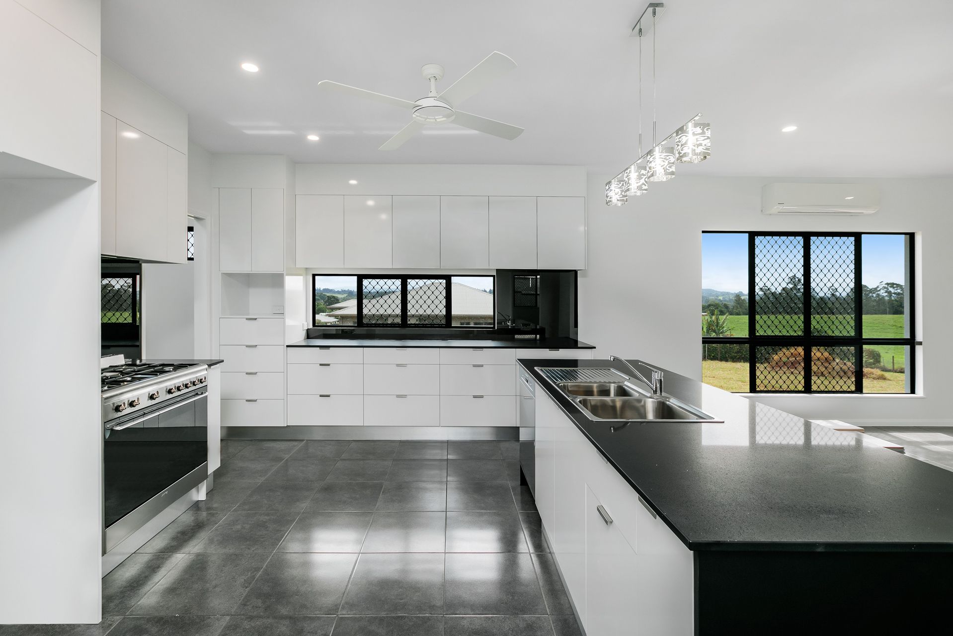 A Modern Kitchen With White Cabinetry, Black Countertops — Ashlee Jones Homes in Gordonvale, QLD