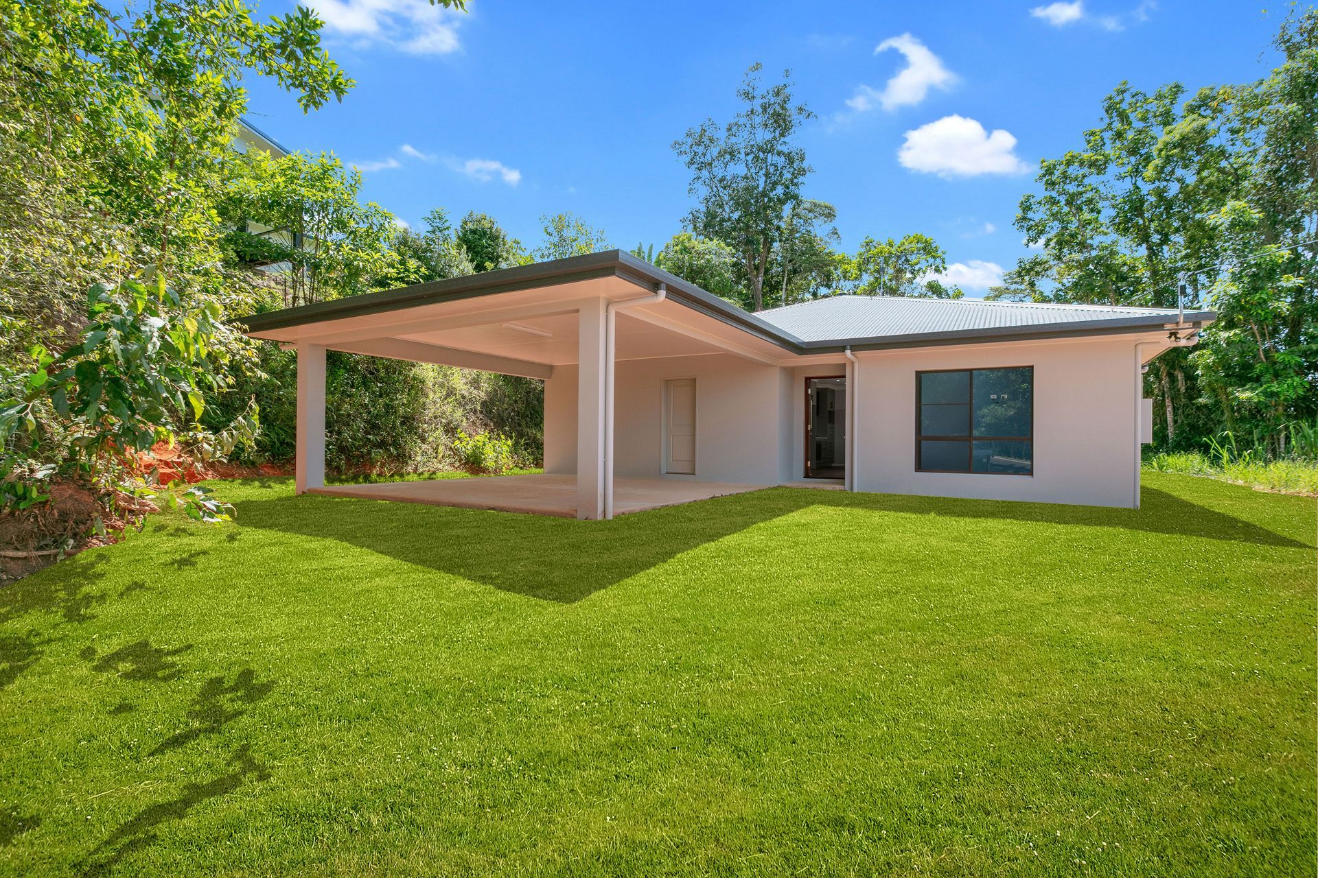A Light-colored House With a Large Covered Patio and a Metal Roof — Ashlee Jones Homes in Gordonvale, QLD