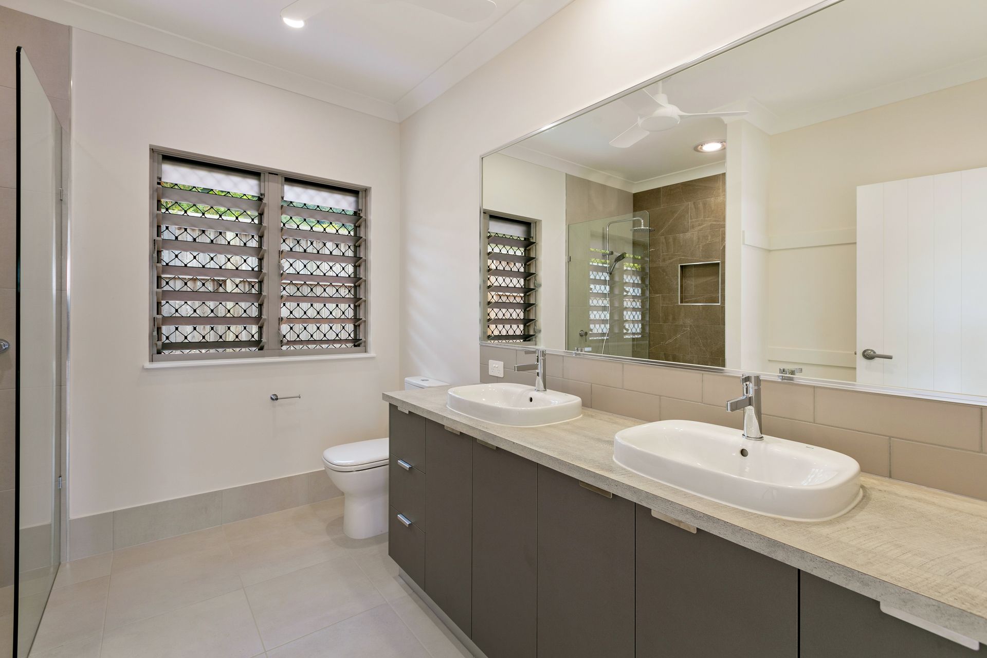 A Modern Bathroom With a Double Vanity, Large Mirror — Ashlee Jones Homes in Gordonvale, QLD