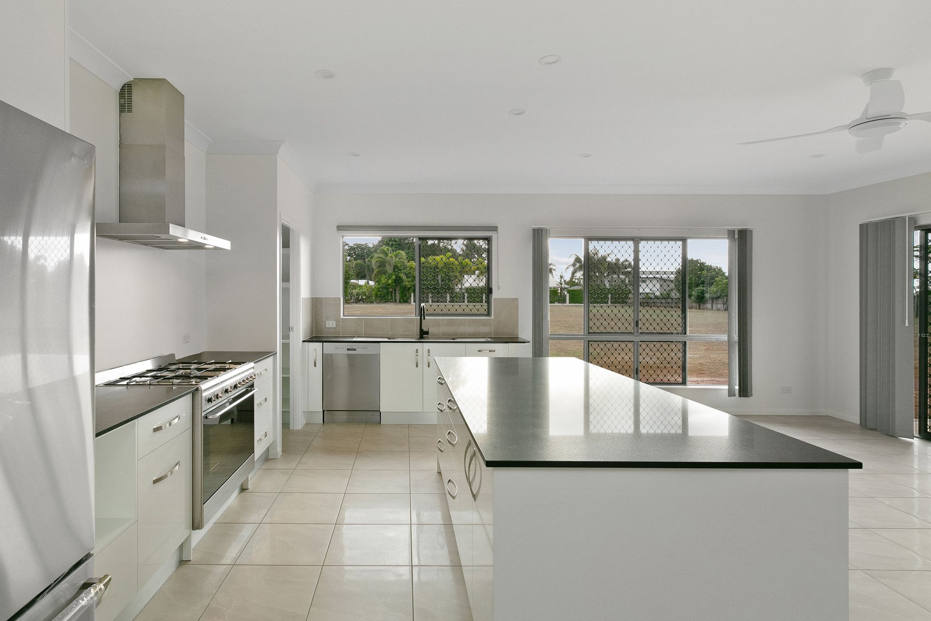 A Modern Kitchen With White Cabinetry, Stainless Steel Appliances — Ashlee Jones Homes in Gordonvale, QLD