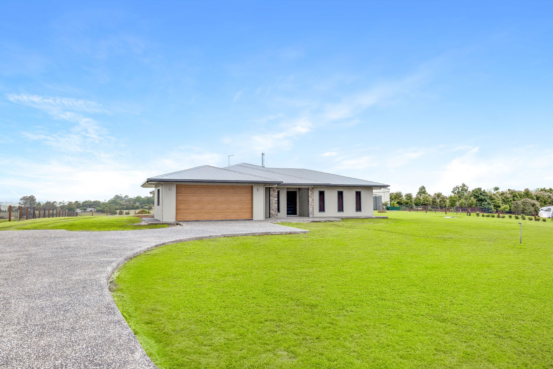 A Single-story, Light-colored Modern House With a Wooden Garage Door — Ashlee Jones Homes in Gordonvale, QLD
