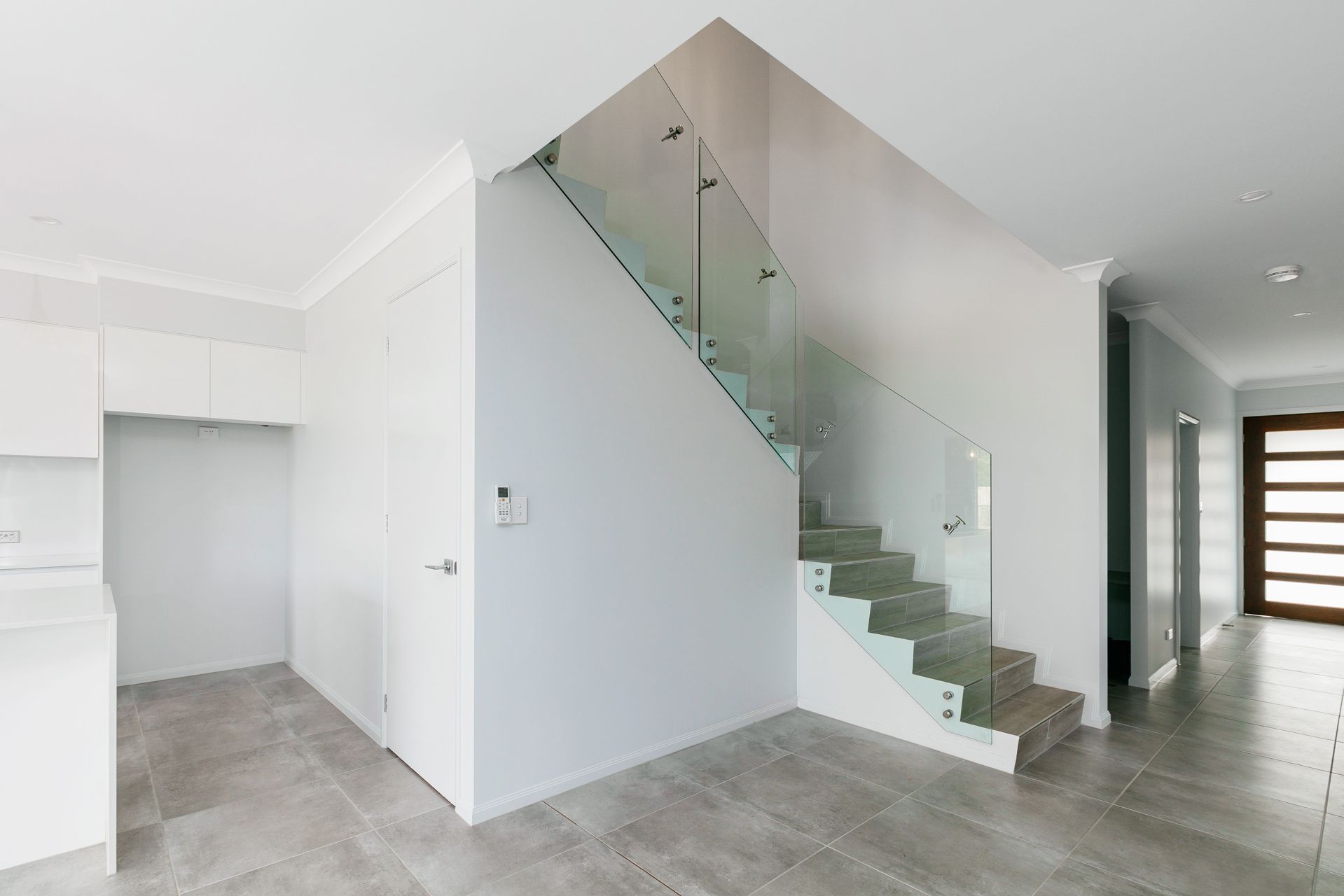 A Staircase With Wooden Steps and a Modern Glass Railing in a Bright — Ashlee Jones Homes in Gordonvale, QLD