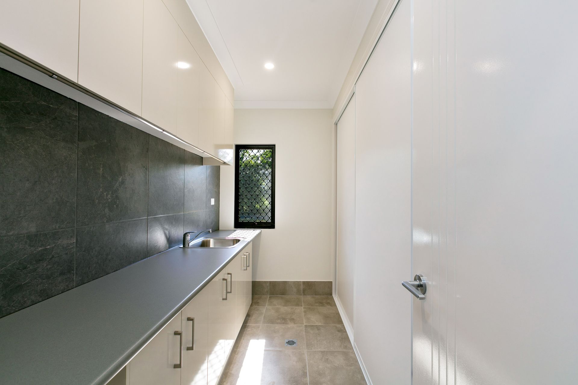 A Modern Laundry Room With Beige Cabinetry — Ashlee Jones Homes in Gordonvale, QLD