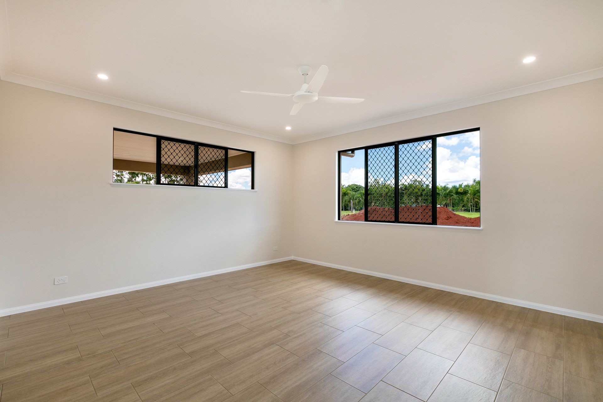 An Empty Room With Beige Walls, Light Wood-look Flooring — Ashlee Jones Homes in Gordonvale, QLD