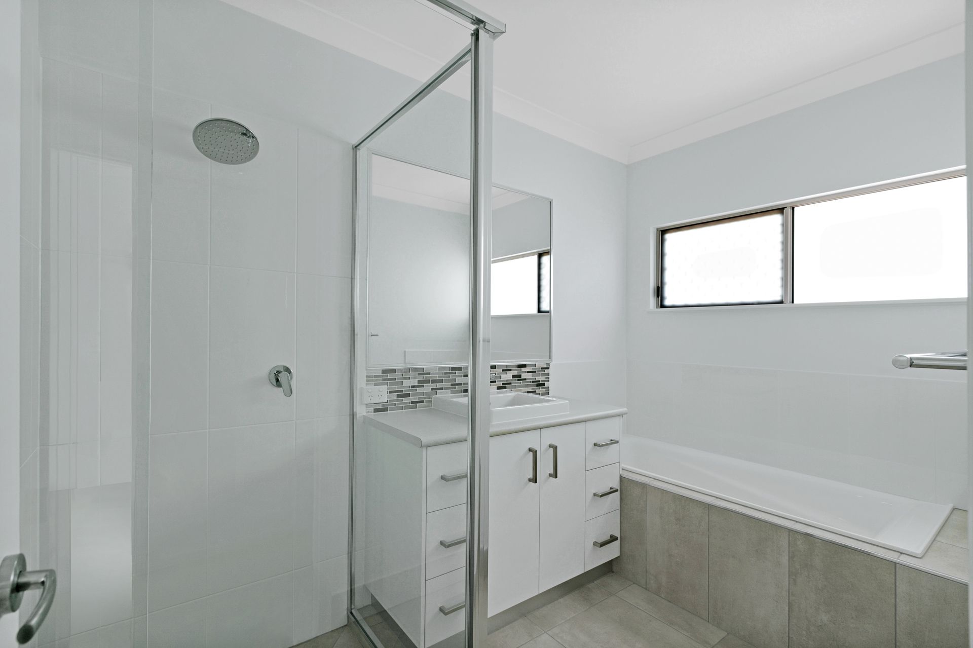 A Modern Bathroom Featuring a White Vanity With a Mirror — Ashlee Jones Homes in Gordonvale, QLD