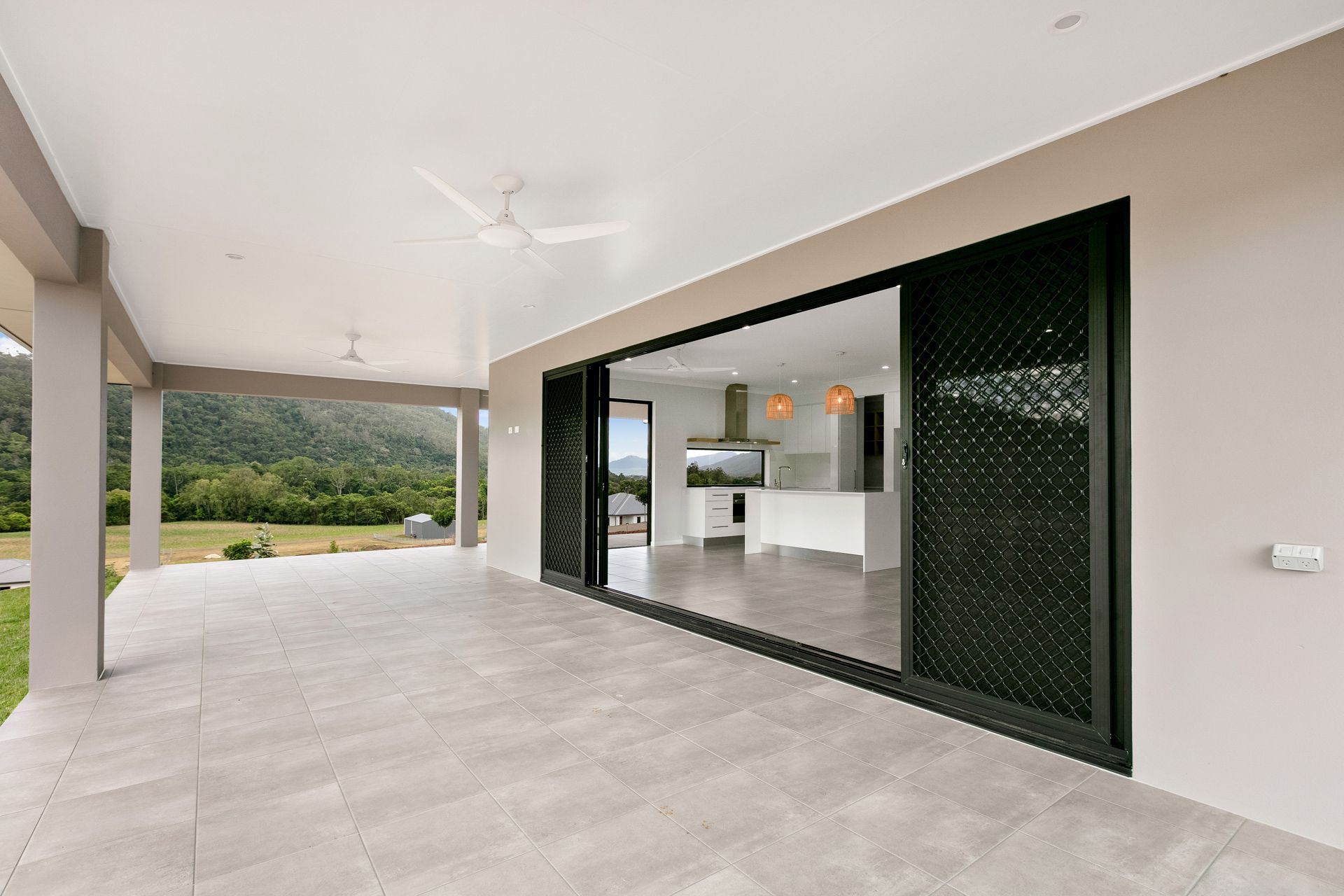 A Spacious, Covered Outdoor Patio Featuring Light-gray Tiled Flooring — Ashlee Jones Homes in Gordonvale, QLD