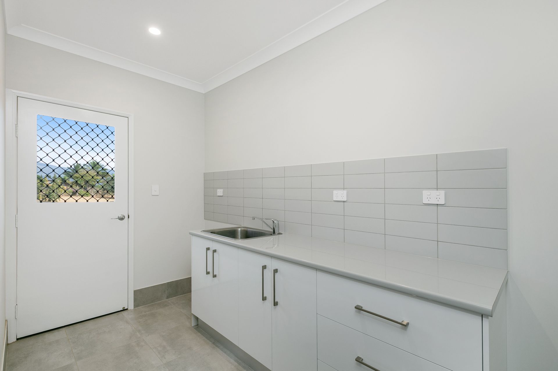 A Modern Laundry Room With White Cabinetry — Ashlee Jones Homes in Gordonvale, QLD