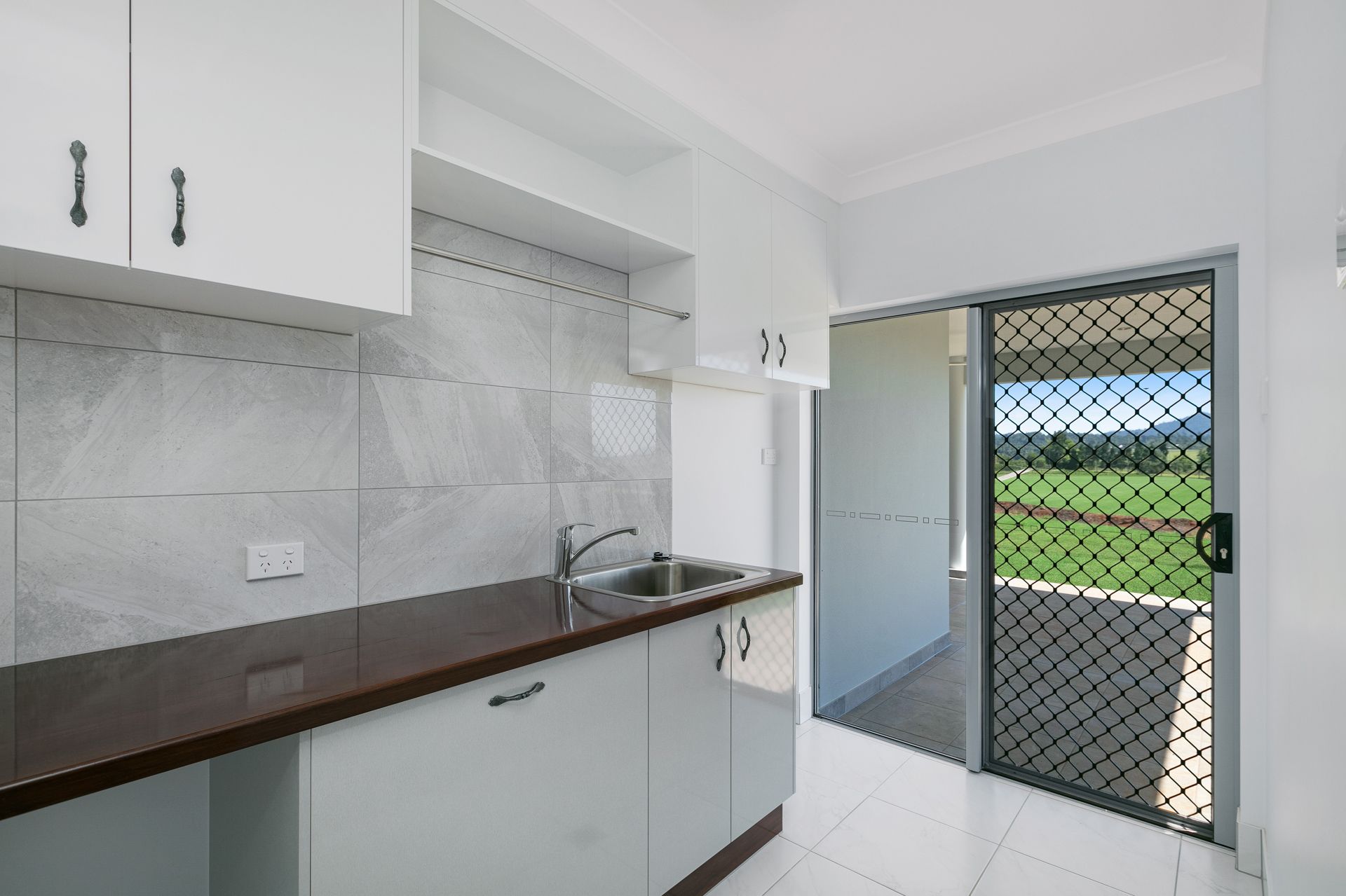 A Bright Kitchen With White Cabinets, Dark Countertop — Ashlee Jones Homes in Gordonvale, QLD