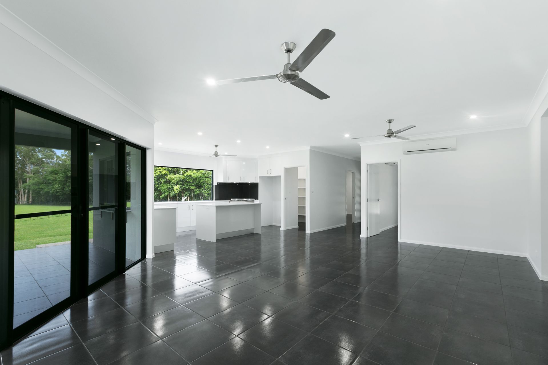 An Open-concept Living Area With Dark Tile Flooring — Ashlee Jones Homes in Gordonvale, QLD