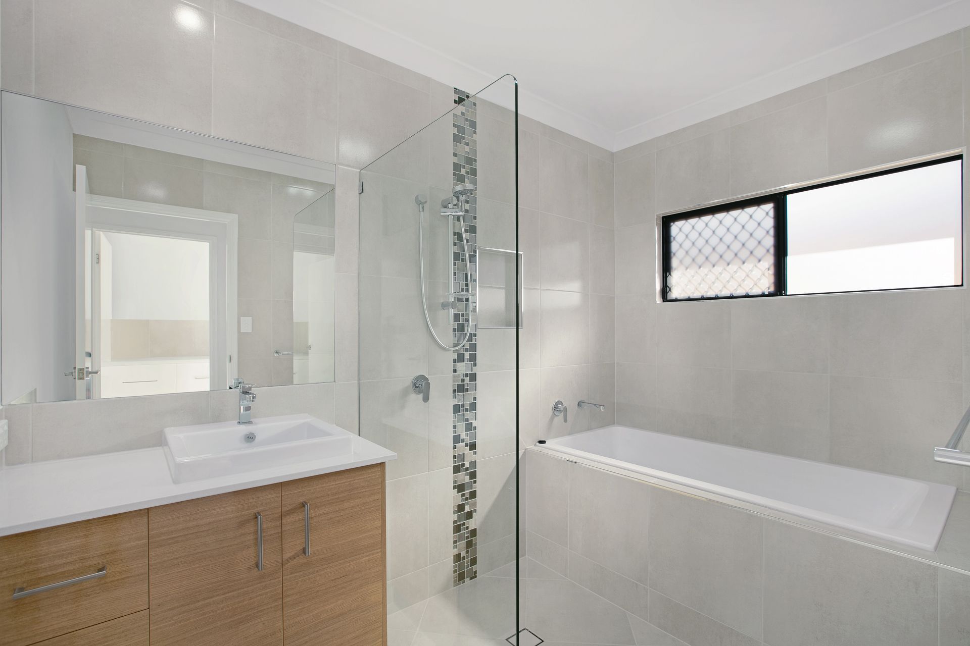 Modern Bathroom With Light Grey Tiles, a Wooden Vanity With a White Basin — Ashlee Jones Homes in Gordonvale, QLD