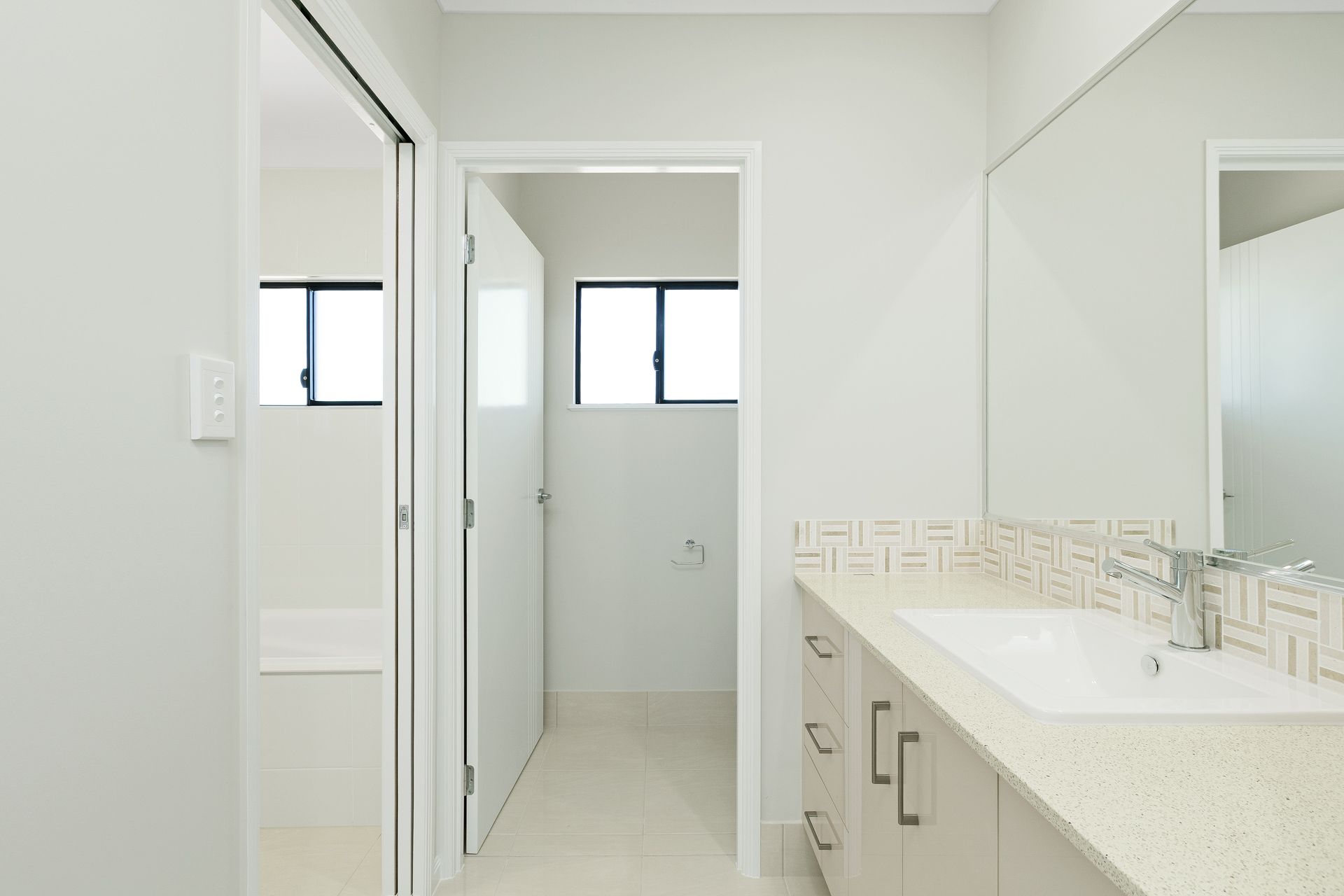 A Brightly Lit Bathroom With a Vanity, Sink, Large Mirror — Ashlee Jones Homes in Gordonvale, QLD