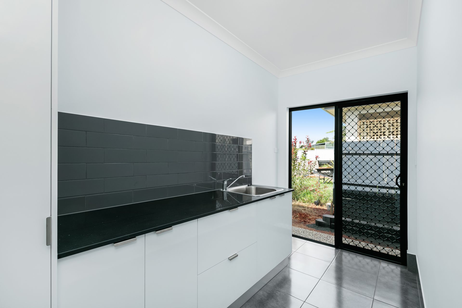 A Modern Laundry Room With White Cabinets — Ashlee Jones Homes in Gordonvale, QLD