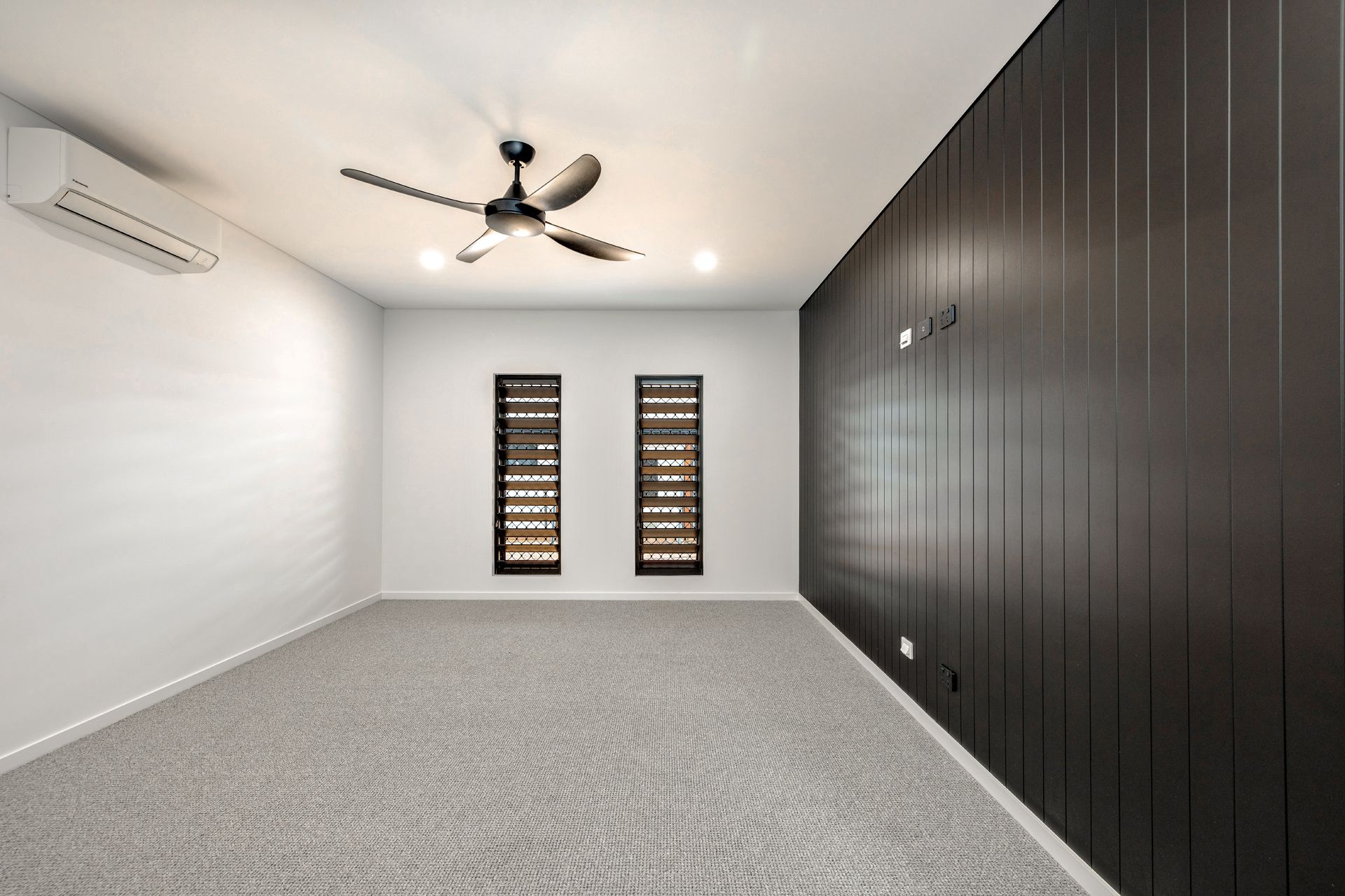 An Empty Room With Grey Carpet, White Walls, a Ceiling Fan — Ashlee Jones Homes in Gordonvale, QLD