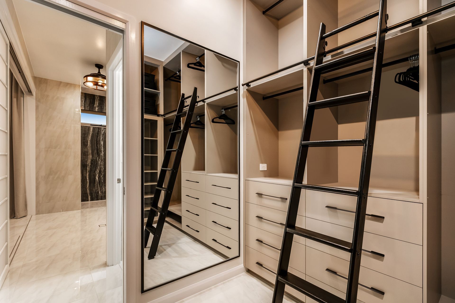A Modern Walk-in Closet Featuring Light Wood Cabinetry — Ashlee Jones Homes in Gordonvale, QLD