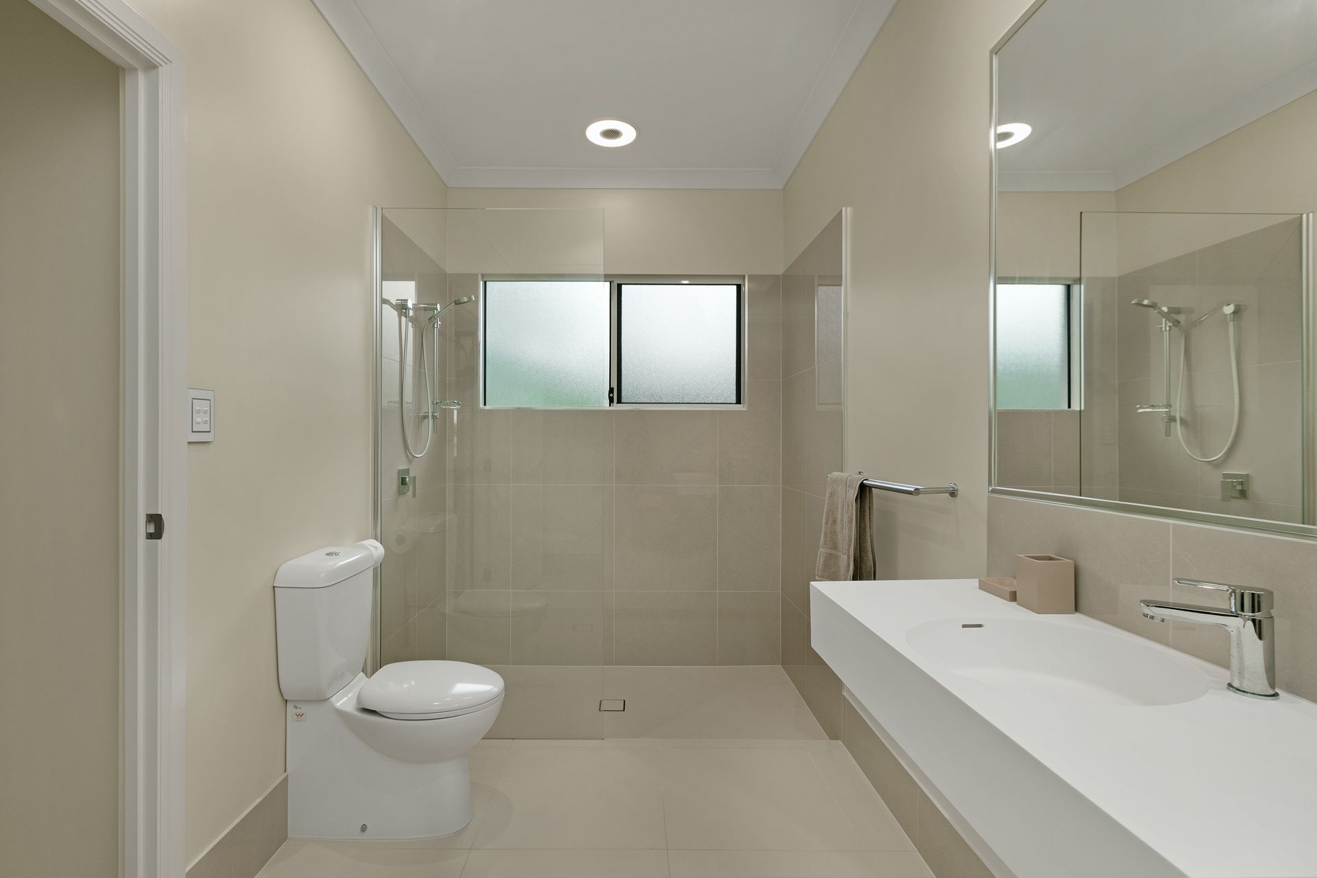 A Neutral-toned Bathroom With a Wall-hung Vanity — Ashlee Jones Homes in Gordonvale, QLD