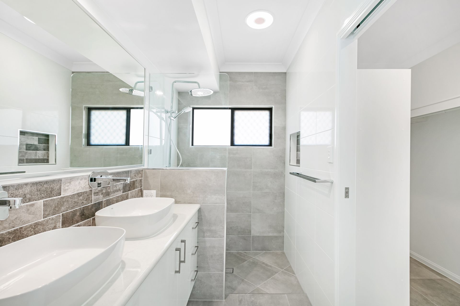 A Modern Bathroom Featuring a White Vanity With Two Vessel Sinks — Ashlee Jones Homes in Gordonvale, QLD