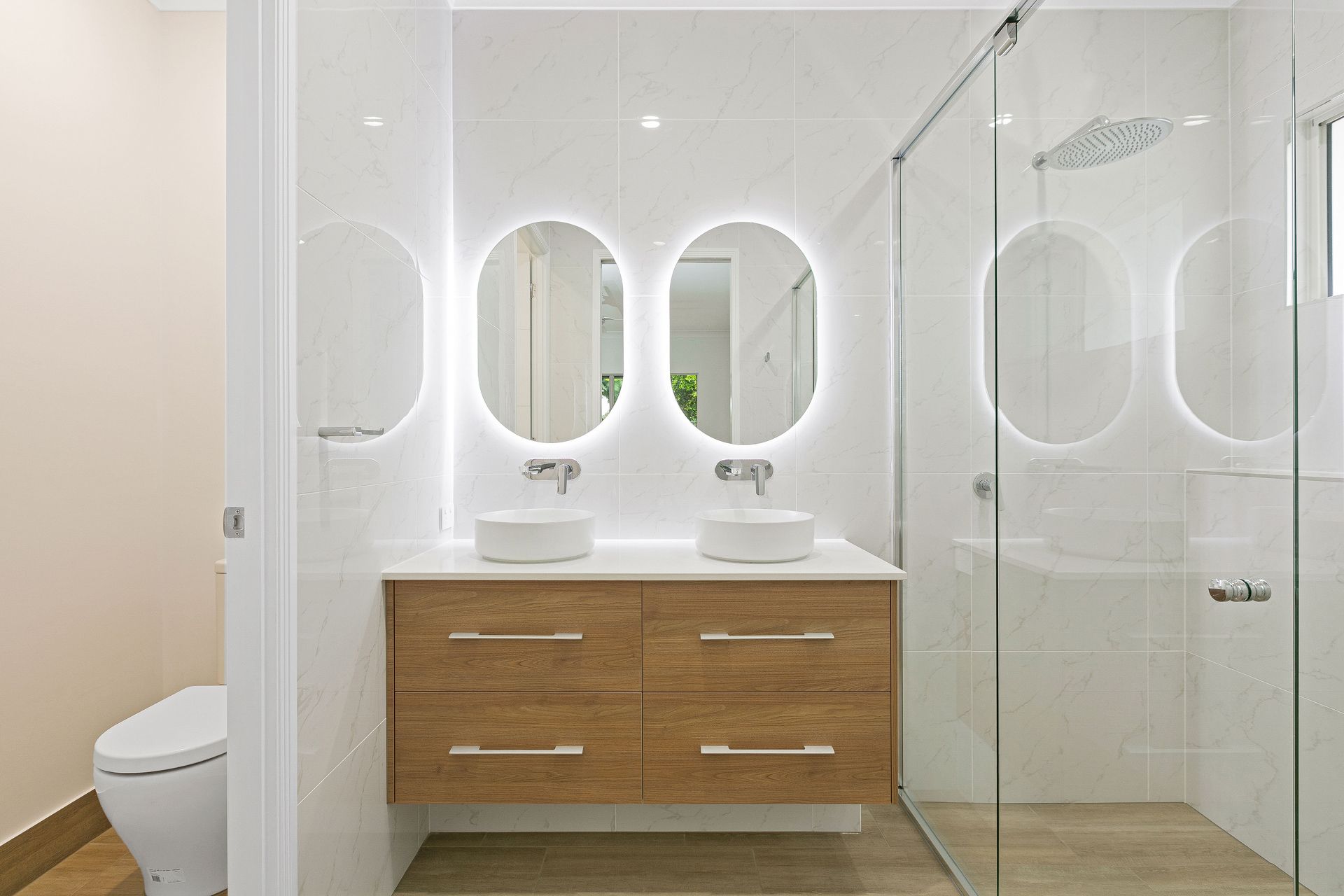 A Modern Bathroom With a Double Vanity, Wood Cabinets — Ashlee Jones Homes in Gordonvale, QLD