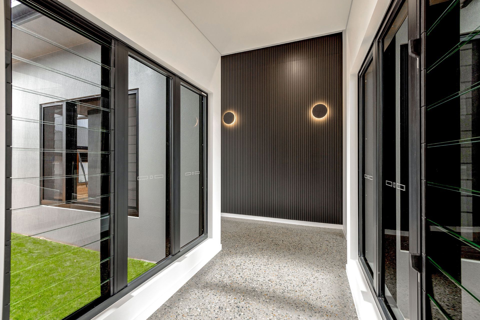 A Modern Hallway With Glass Louvre Windows — Ashlee Jones Homes in Gordonvale, QLD