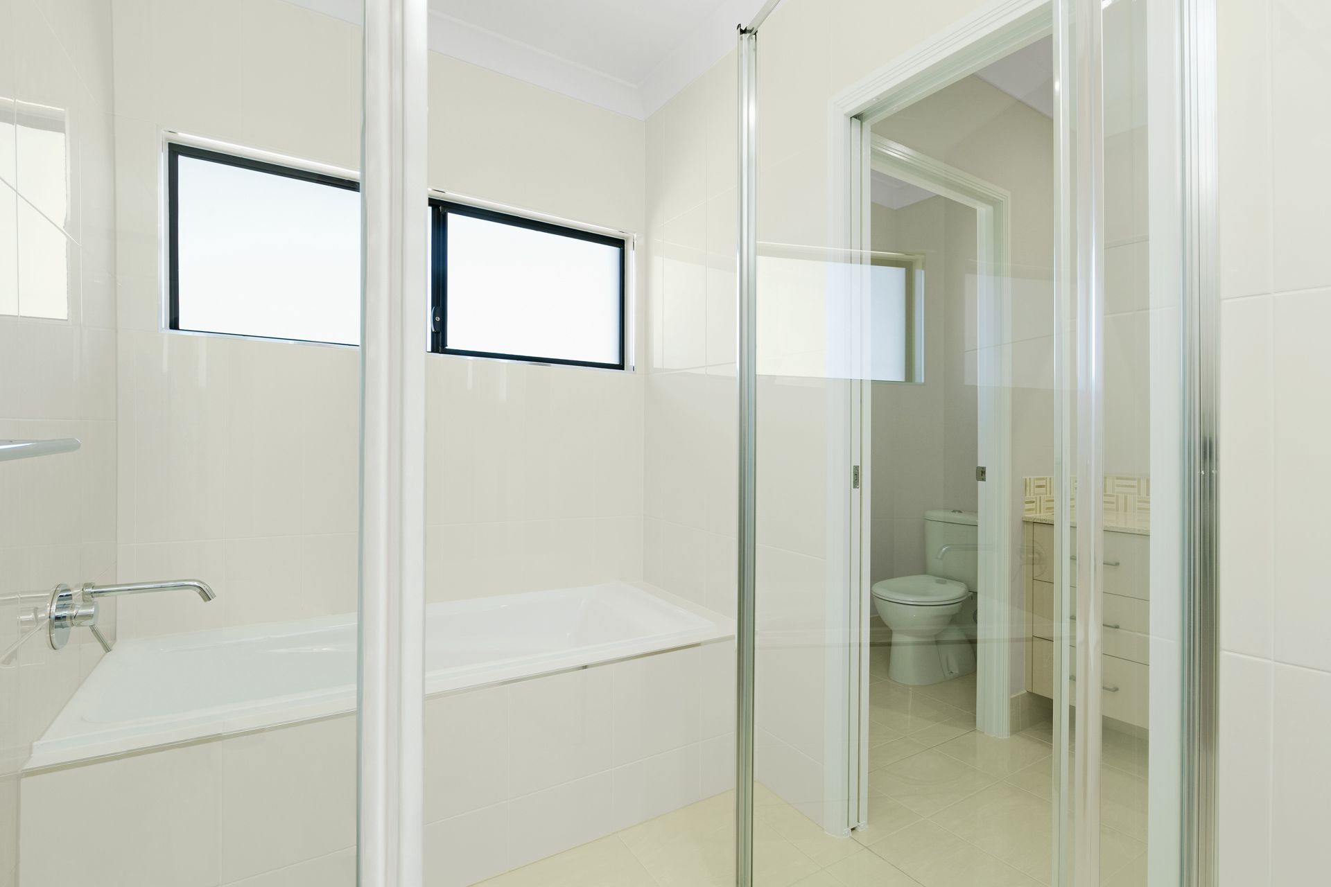 A Bright, Minimalist White Bathroom With a Built-in Bathtub — Ashlee Jones Homes in Gordonvale, QLD