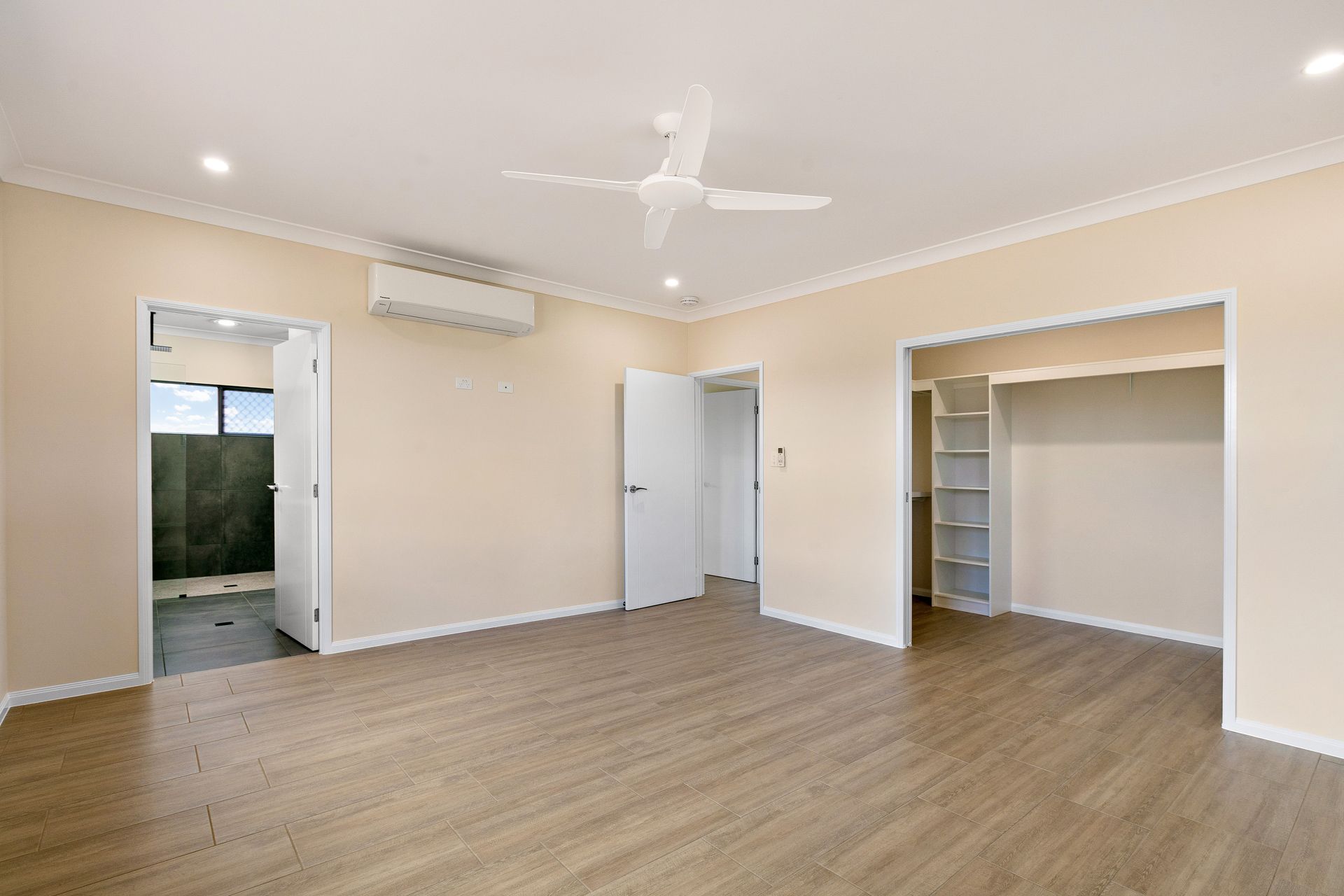 An Empty Bedroom With Light Beige Walls, Wood-look Flooring — Ashlee Jones Homes in Gordonvale, QLD