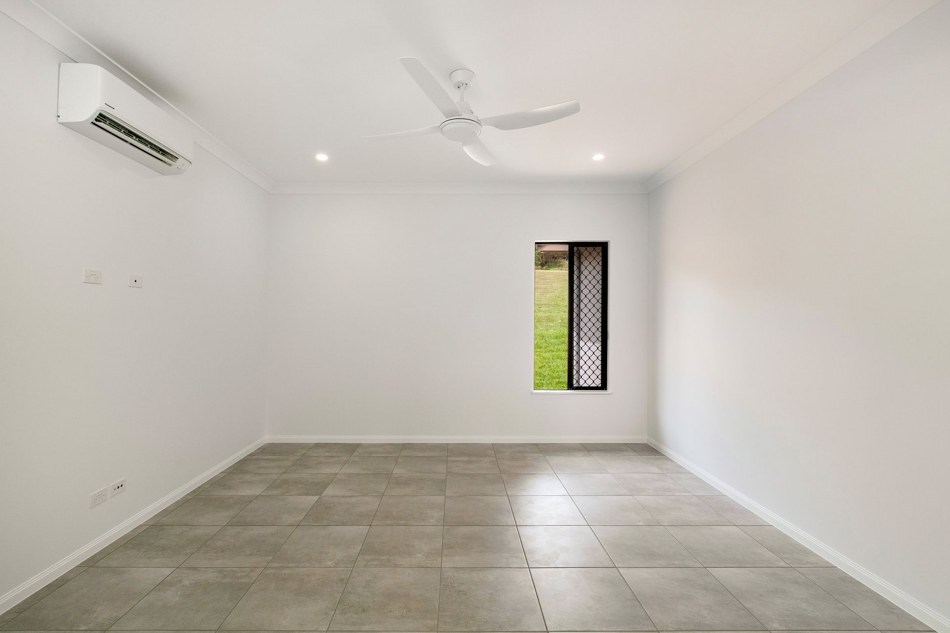 A Bright, Empty Room With Grey Tiled Floors — Ashlee Jones Homes in Gordonvale, QLD