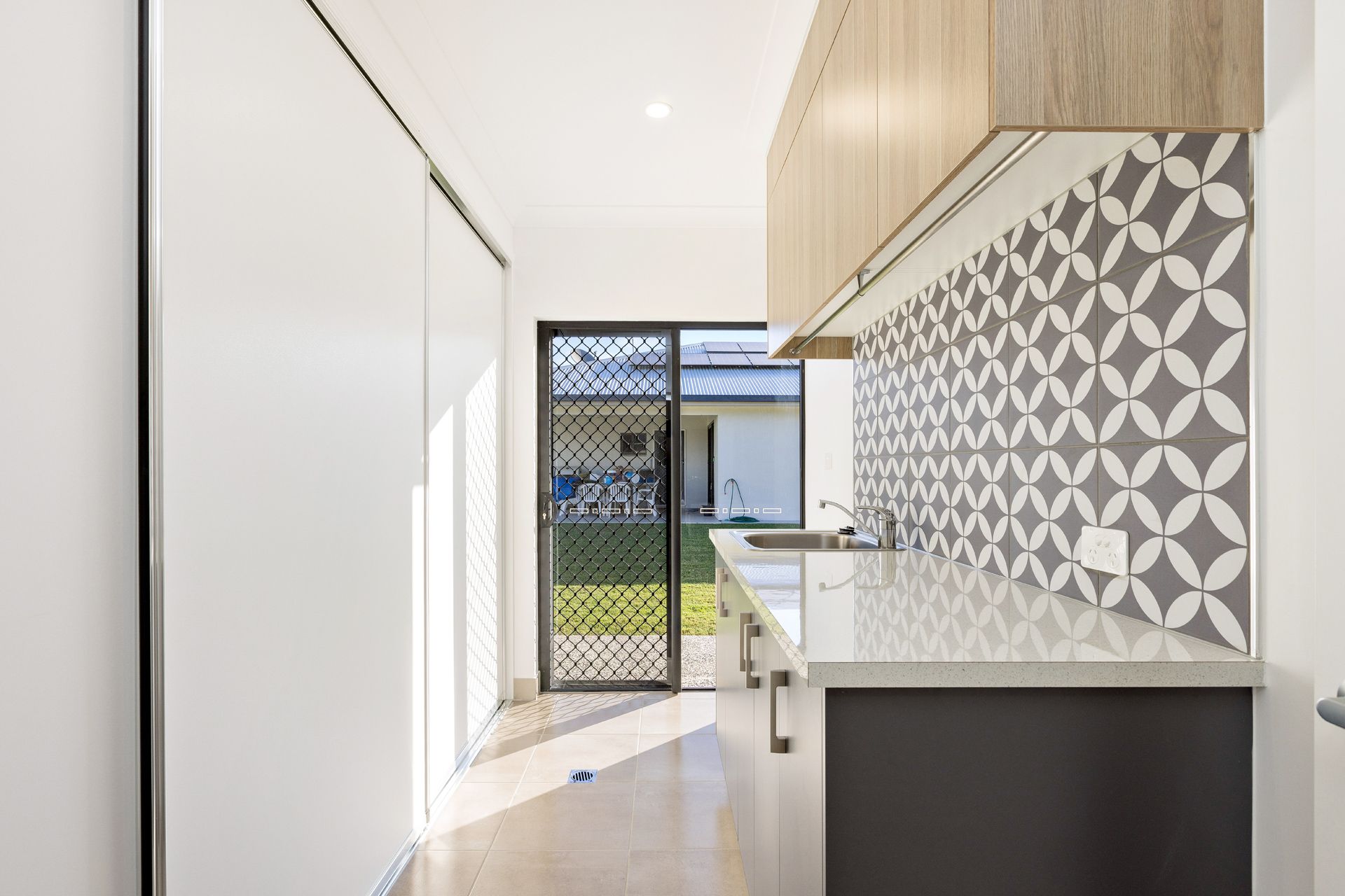 Modern Kitchen Corridor Featuring Light Wood Cabinets — Ashlee Jones Homes in Gordonvale, QLD
