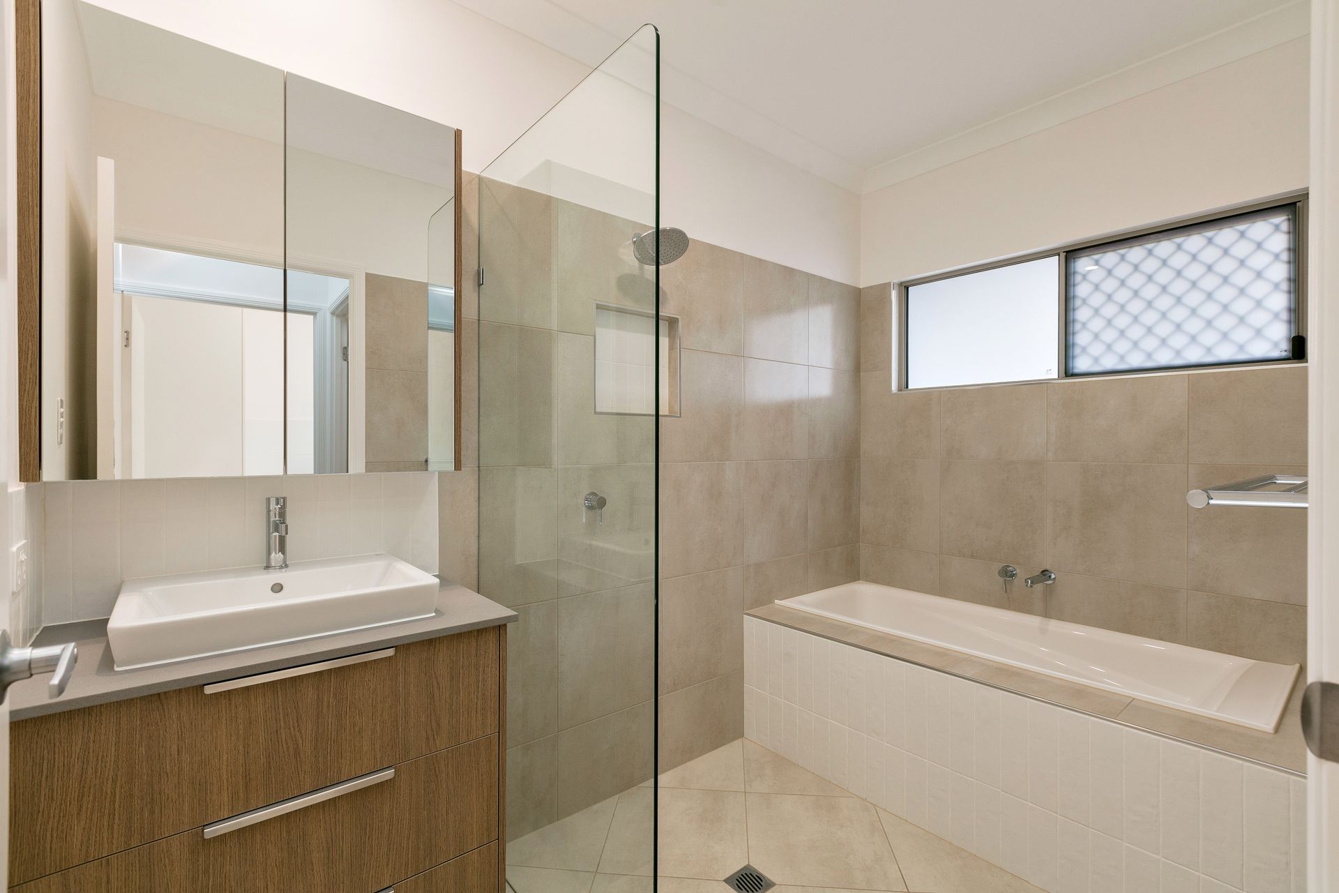 Modern Bathroom With a Wooden Vanity, White Vessel Sink — Ashlee Jones Homes in Gordonvale, QLD