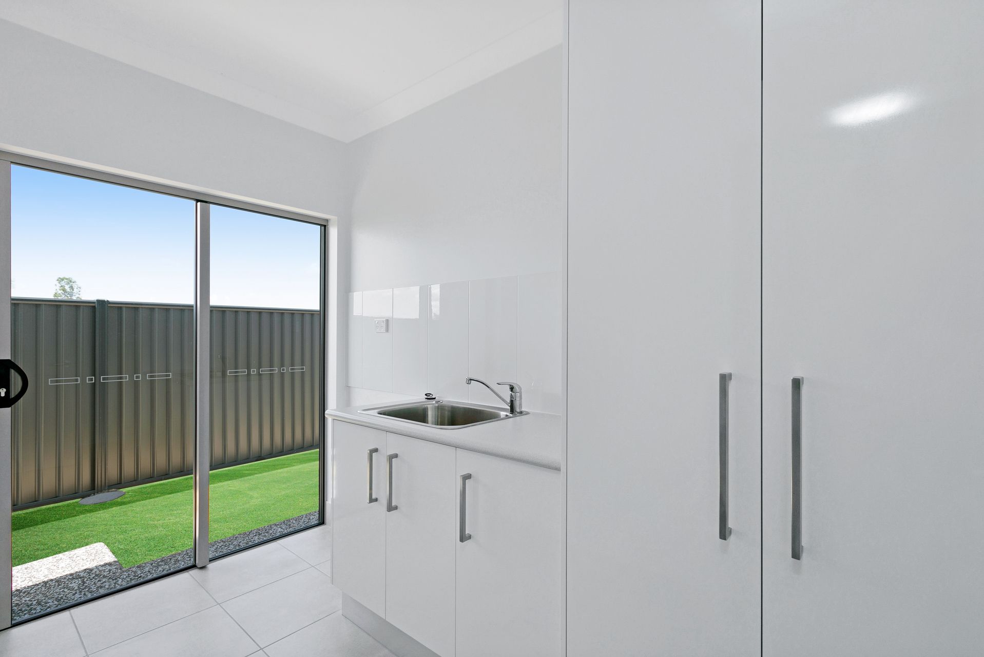 A Kitchen Kitchenette With White Cabinets and a Silver Sink — Ashlee Jones Homes in Gordonvale, QLD