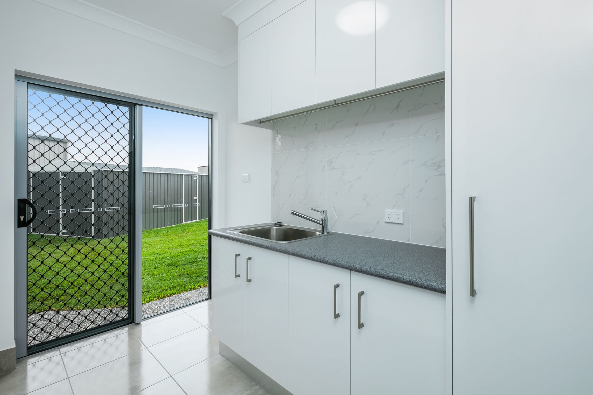A Modern Kitchenette With White Cabinets, a Dark Grey Countertop — Ashlee Jones Homes in Gordonvale, QLD