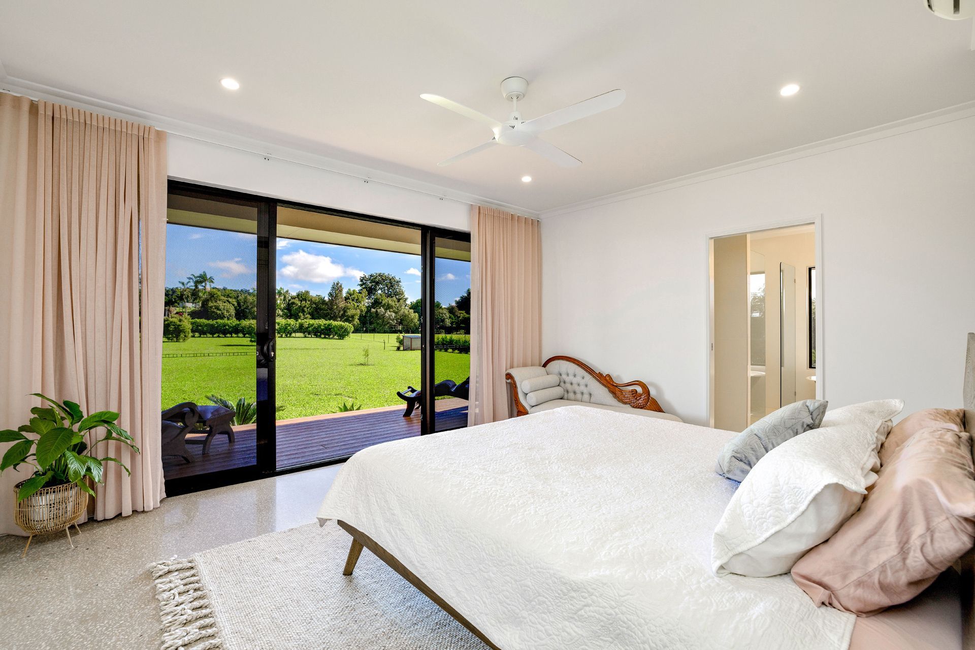 A Light-filled Bedroom With a Large Bed, Ceiling Fan — Ashlee Jones Homes in Gordonvale, QLD