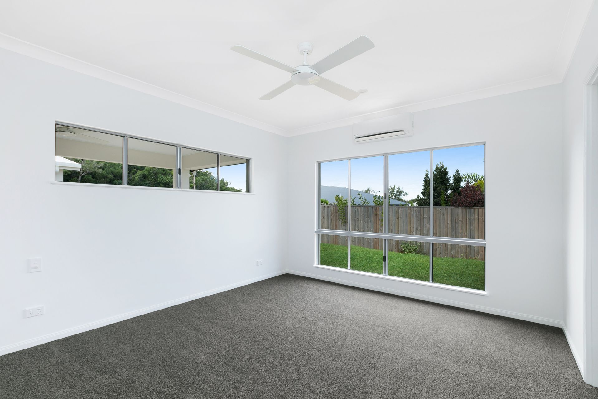 An Empty, White-walled Room With Grey Carpet, a Ceiling Fan — Ashlee Jones Homes in Gordonvale, QLD