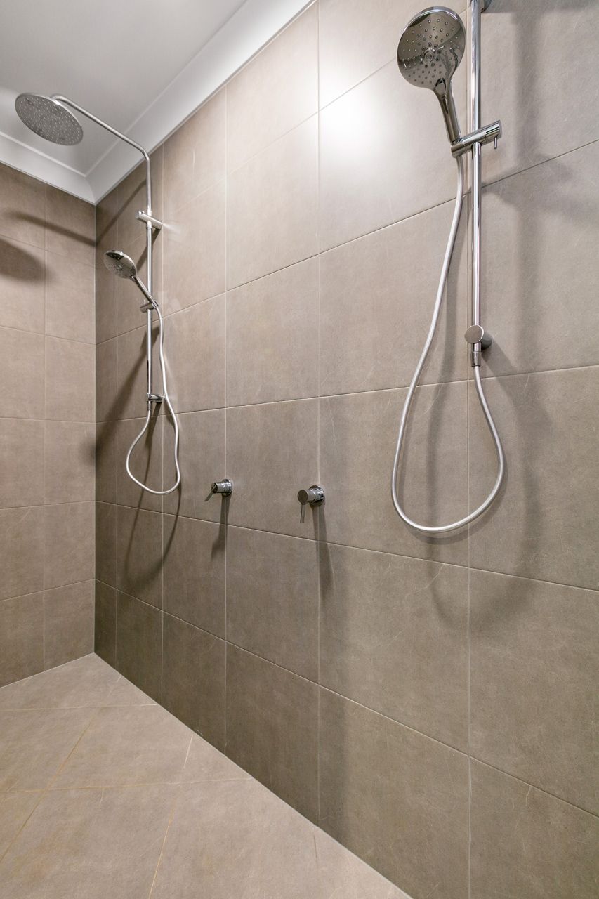 A Double-shower Stall With Light Brown Tiled Walls — Ashlee Jones Homes in Gordonvale, QLD