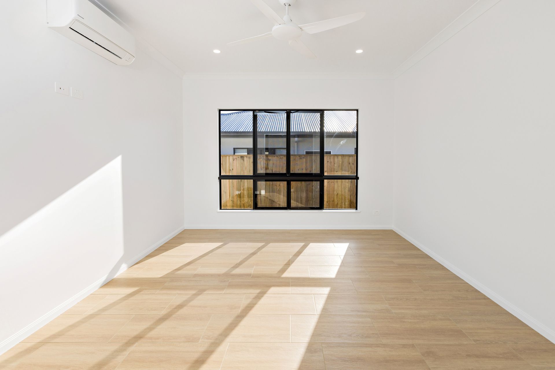 An Empty Room With White Walls, Light Wood Flooring — Ashlee Jones Homes in Gordonvale, QLD