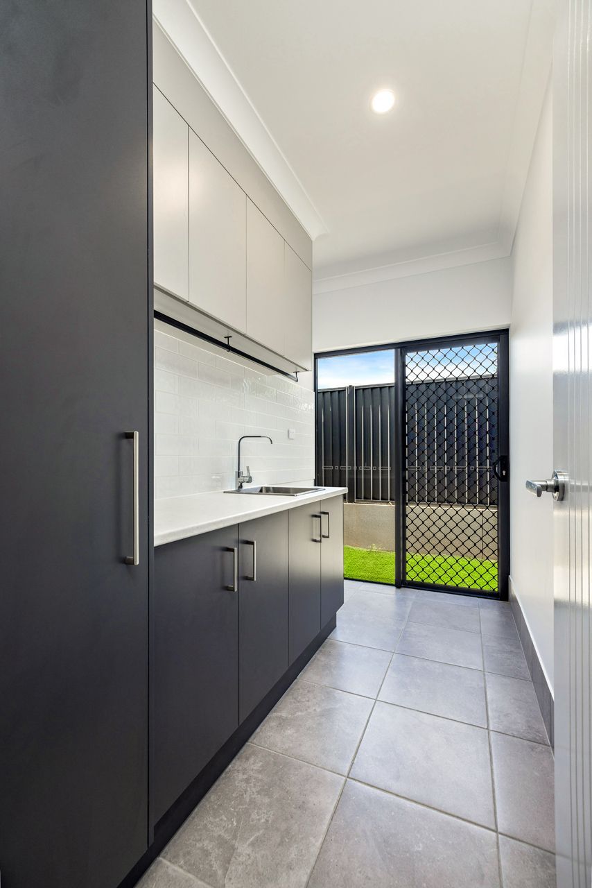 A Laundry Room With Dark Grey Lower Cabinets — Ashlee Jones Homes in Gordonvale, QLD